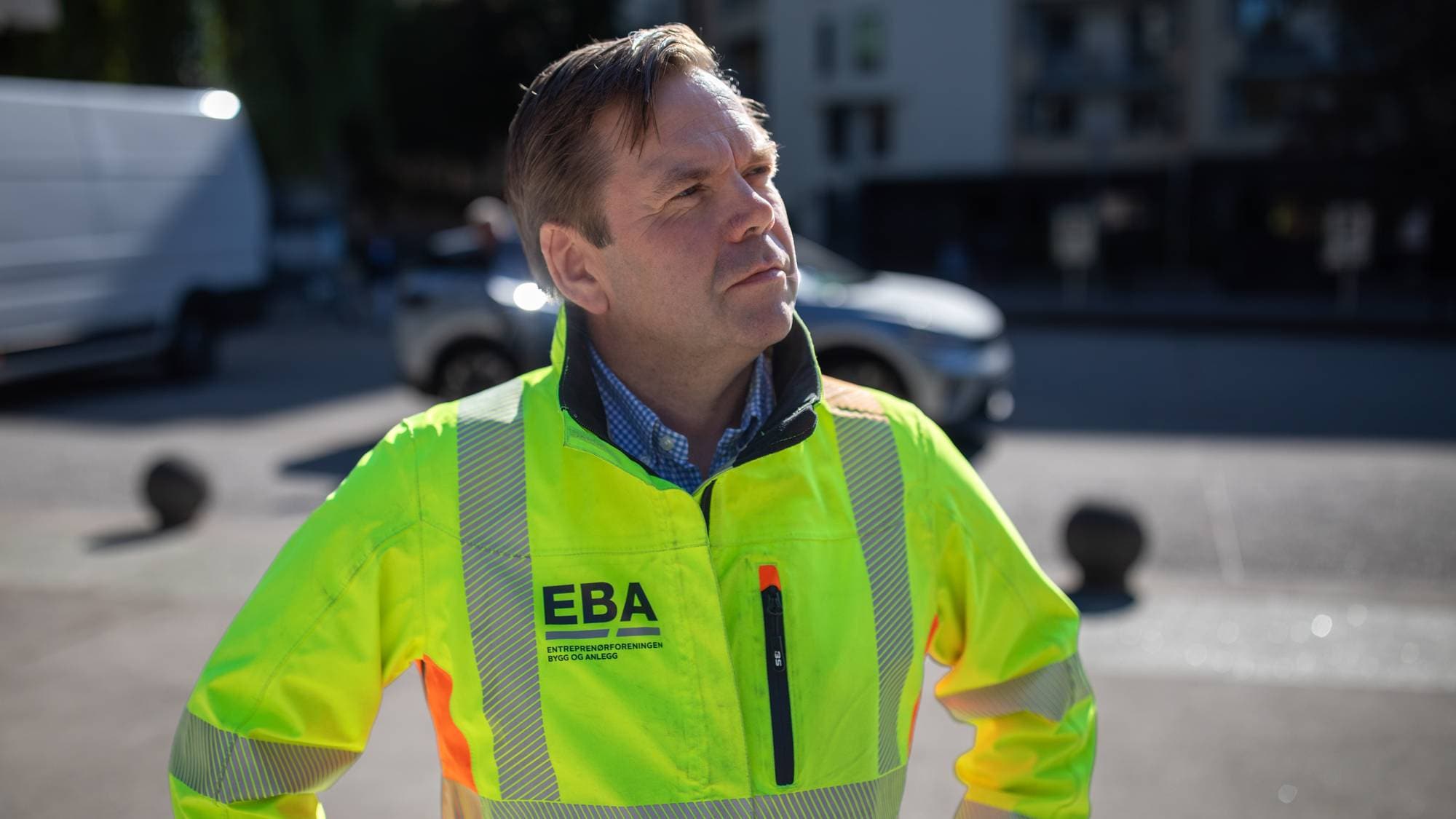 Mann i gul refleksjakke med EBA-logo står utendørs. (Bildebeskrivelsen er laget av en KI-tjeneste)