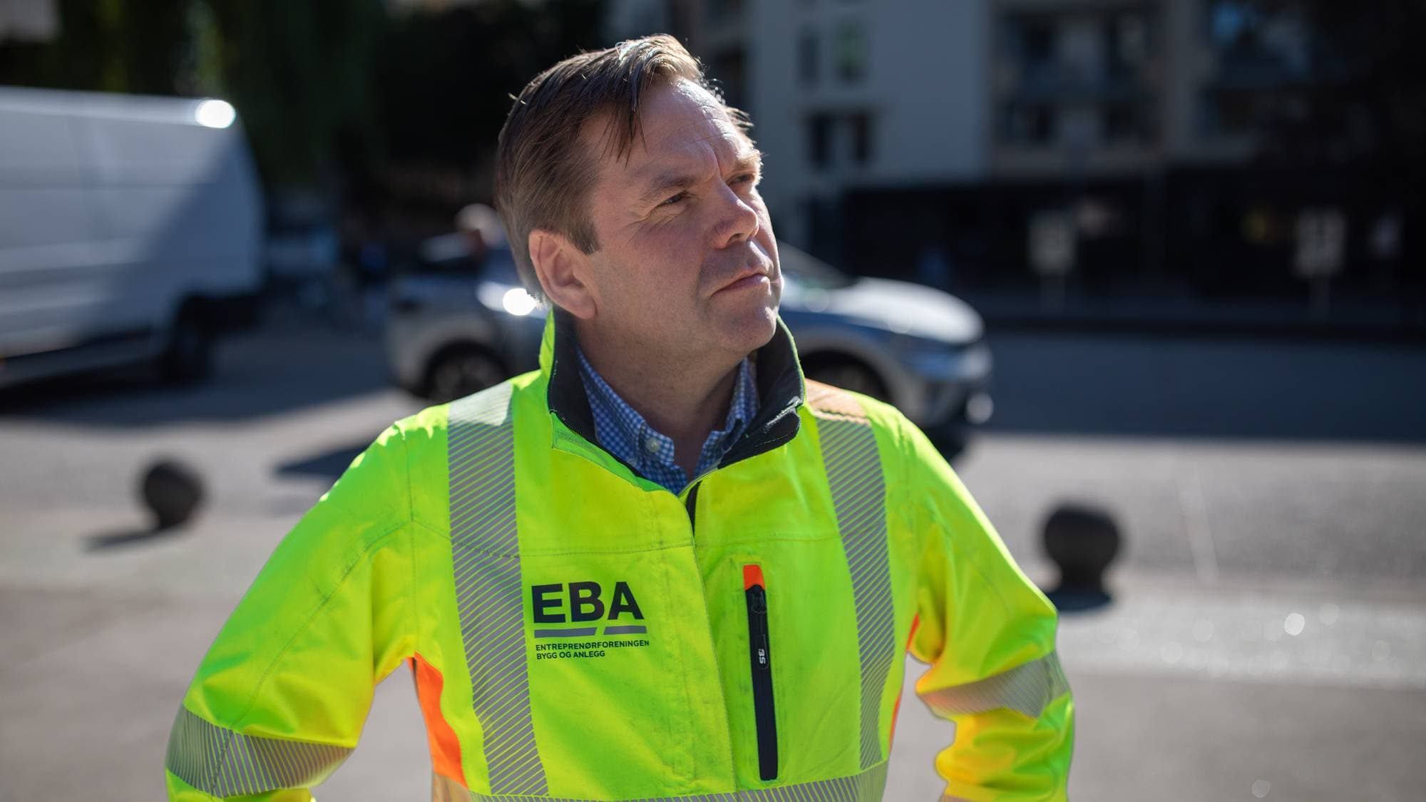 Mann i gul refleksjakke med EBA-logo står utendørs. (Bildebeskrivelsen er laget av en KI-tjeneste)