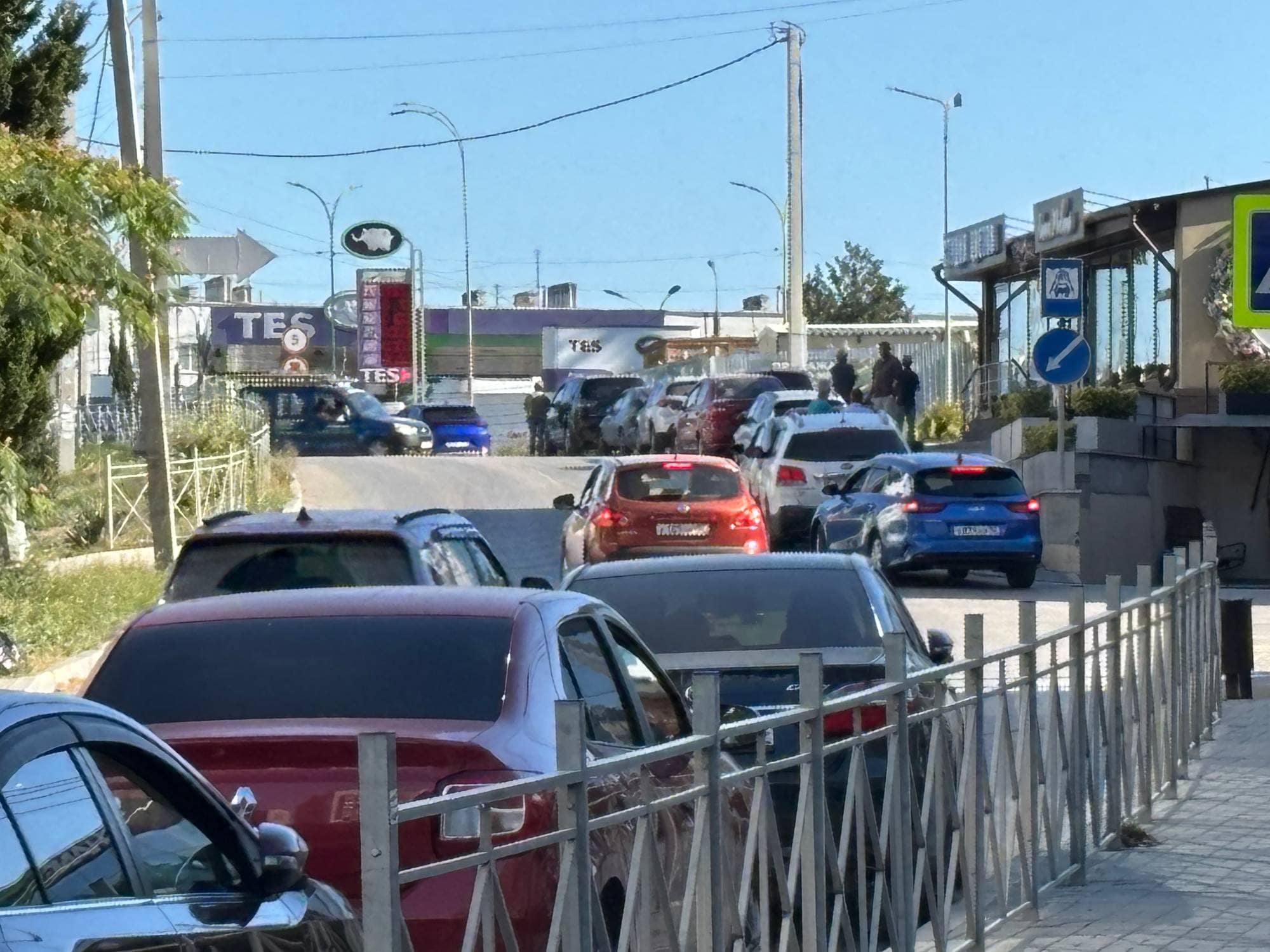 mange biler står i kø foran en bensinstasjon.