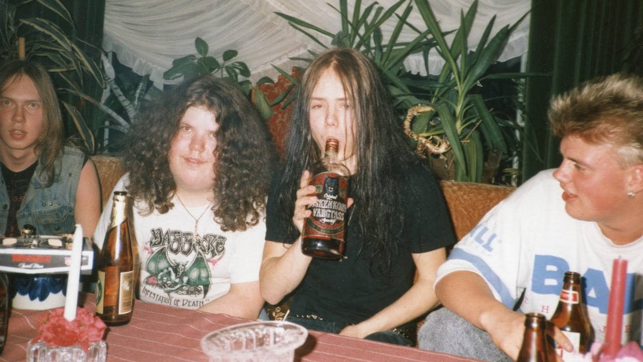 Jon «Metallion» Kristiansen og Øystein Aarseth som ungdom på fest. Øystein sitter med en flaske brennevin i hendene som han ser ut til å drikke fra.