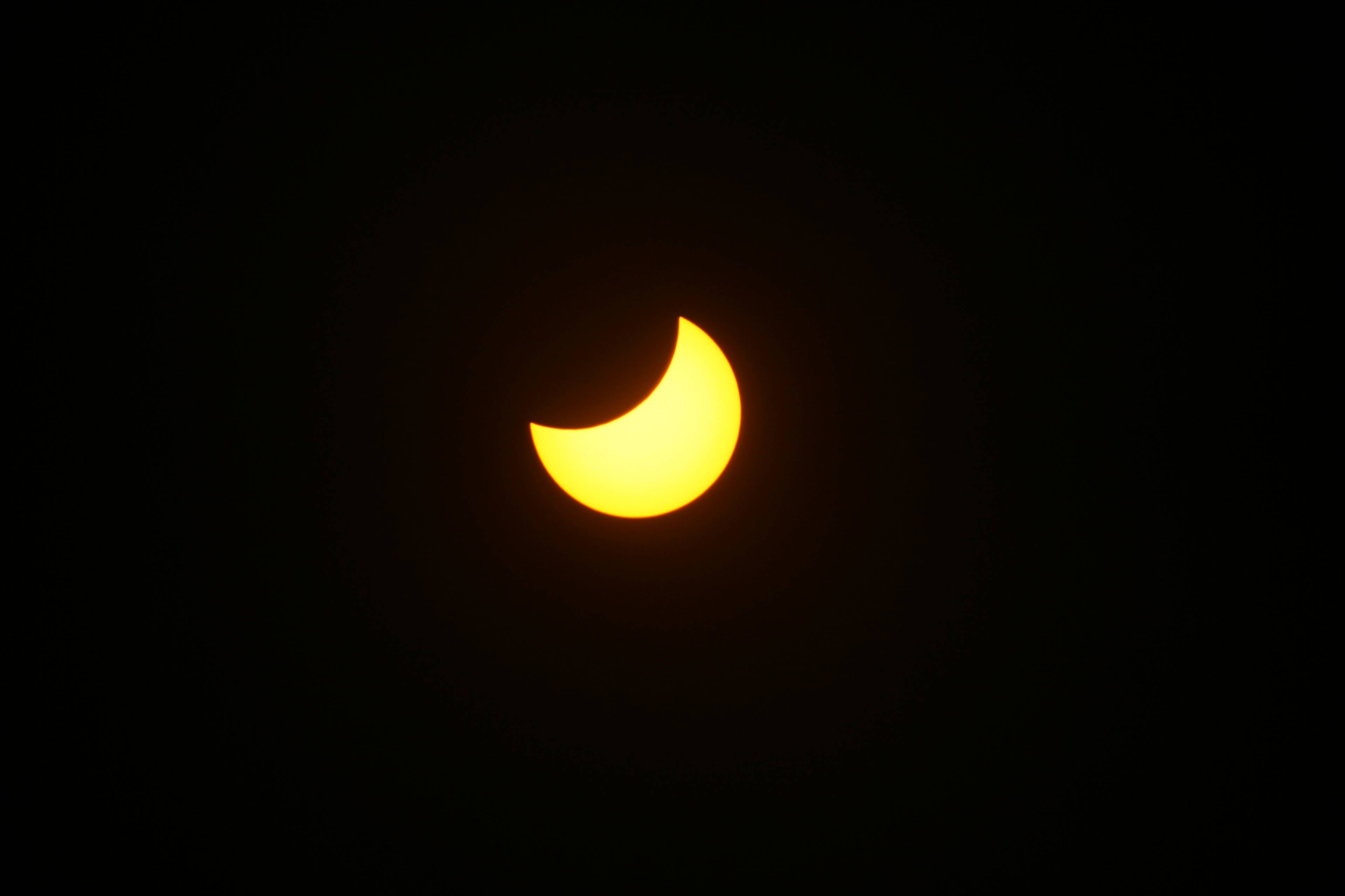 Delvis solformørkelse sett mot en mørk himmel. (Bildebeskrivelsen er laget av en KI-tjeneste)