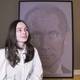 Foto: SYNNØVE SUNDBY FALLMYR / NRK Una joven sentada frente a un gran retrato de Vladimir Putin en su apartamento. El retrato está dibujado en forma de más de 40.000 penes diminutos.
