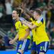 Matias Delacroix / AP,NTB Tre svenske fotballspillere feirer et mål på en bane. Spilleren i forgrunnen, med nummer 19 på drakten, jubler med armene i været. En annen spiller, med nummer 21, klapper ham på skulderen. I bakgrunnen sees tilskuere på tribunen. (Bildebeskrivelsen er laget av en KI-tjeneste)