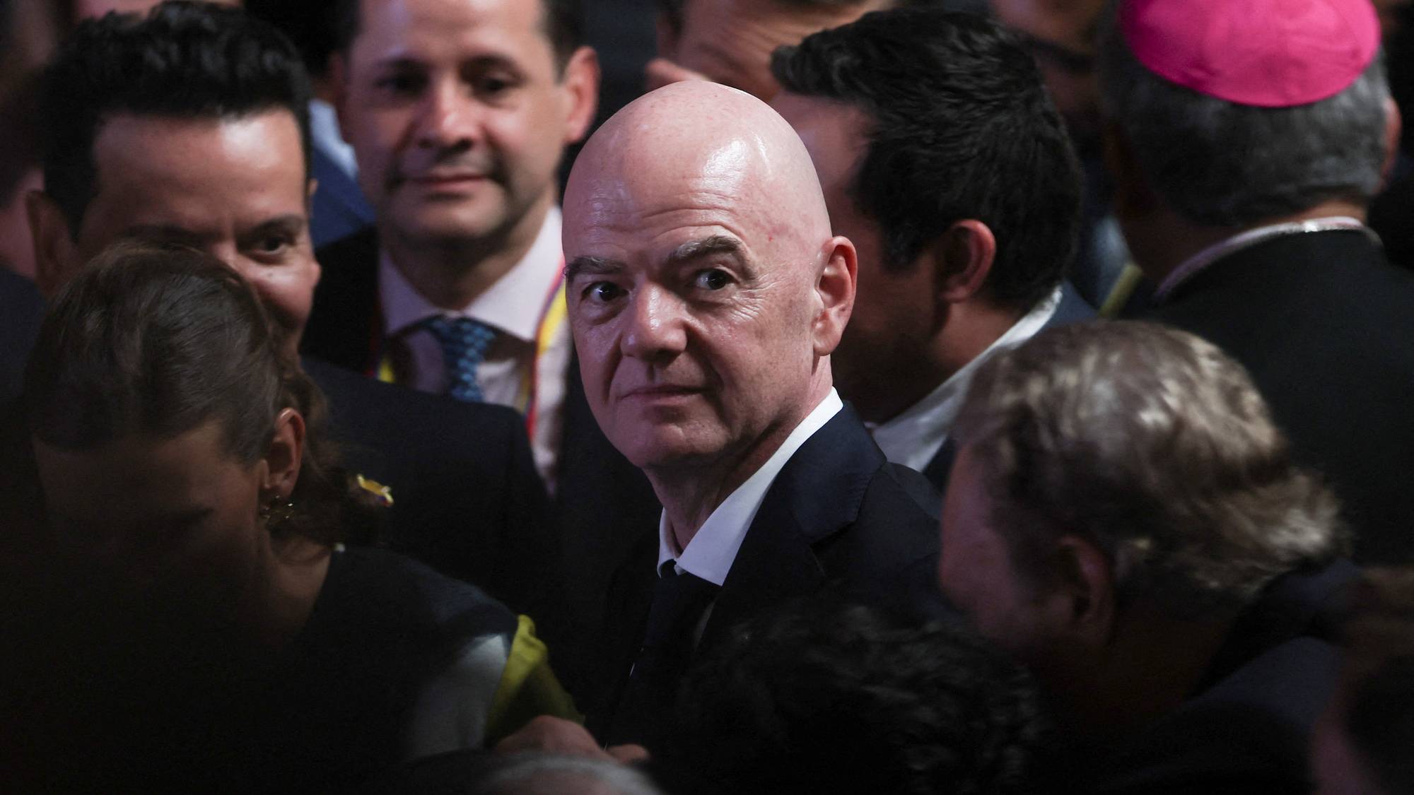 Gianni Infantino omgitt av en folkemengde. En person med rosa kalott sees til høyre. (Bildebeskrivelsen er laget av en KI-tjeneste)