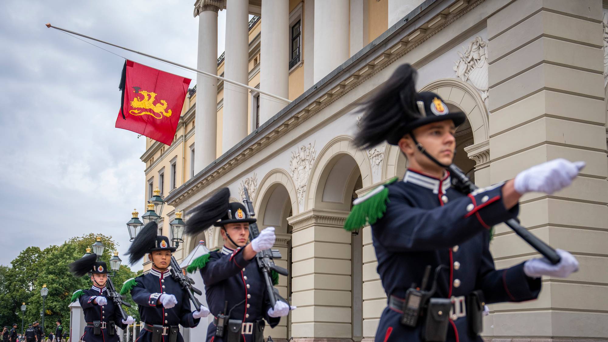 Kongeflagget med sørgeflor henger fra Slottsbalkongen mens gardister passerer Slottet