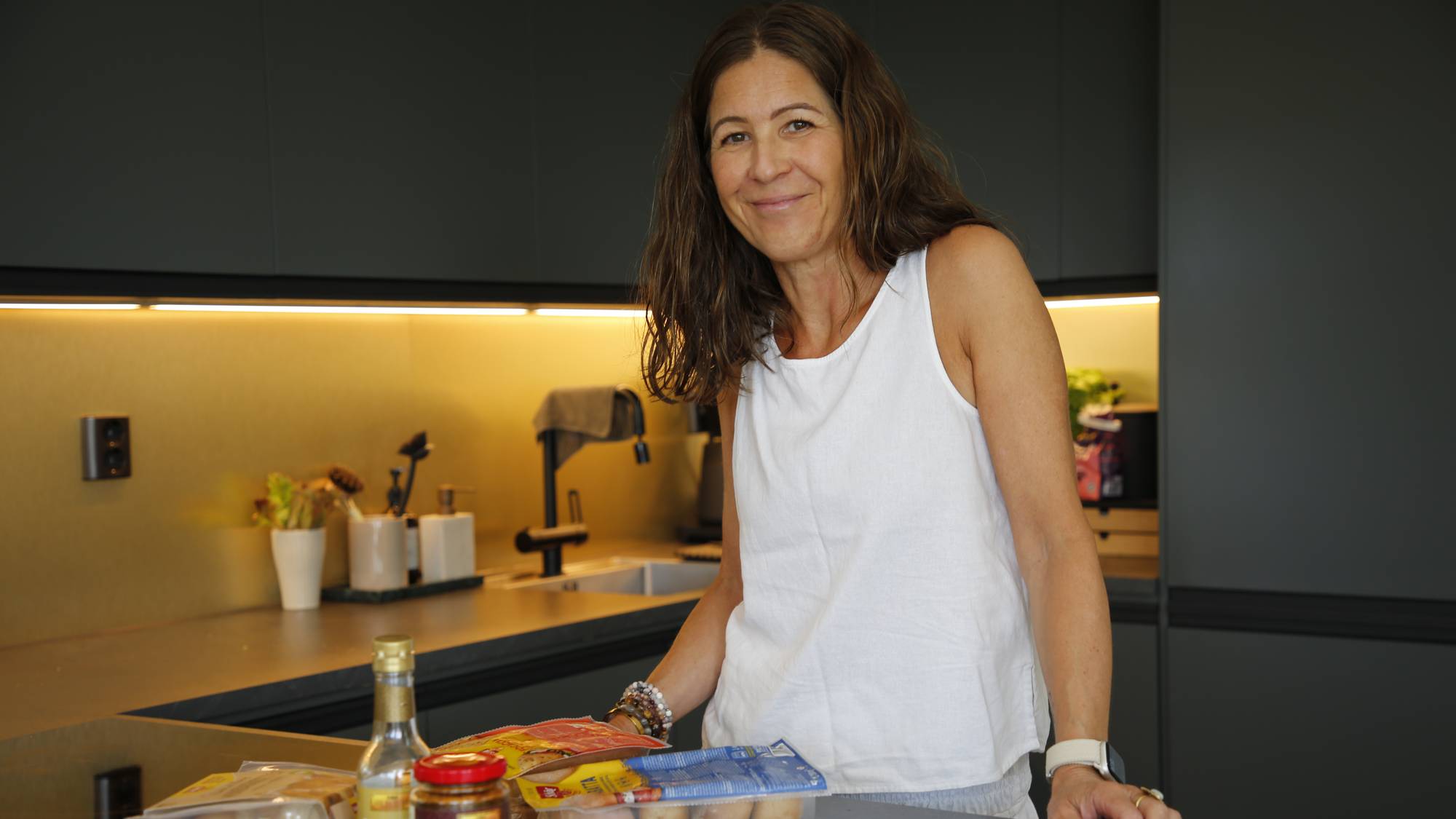 en kvinne i hvitt viser frem sine glutenfrie matvarer