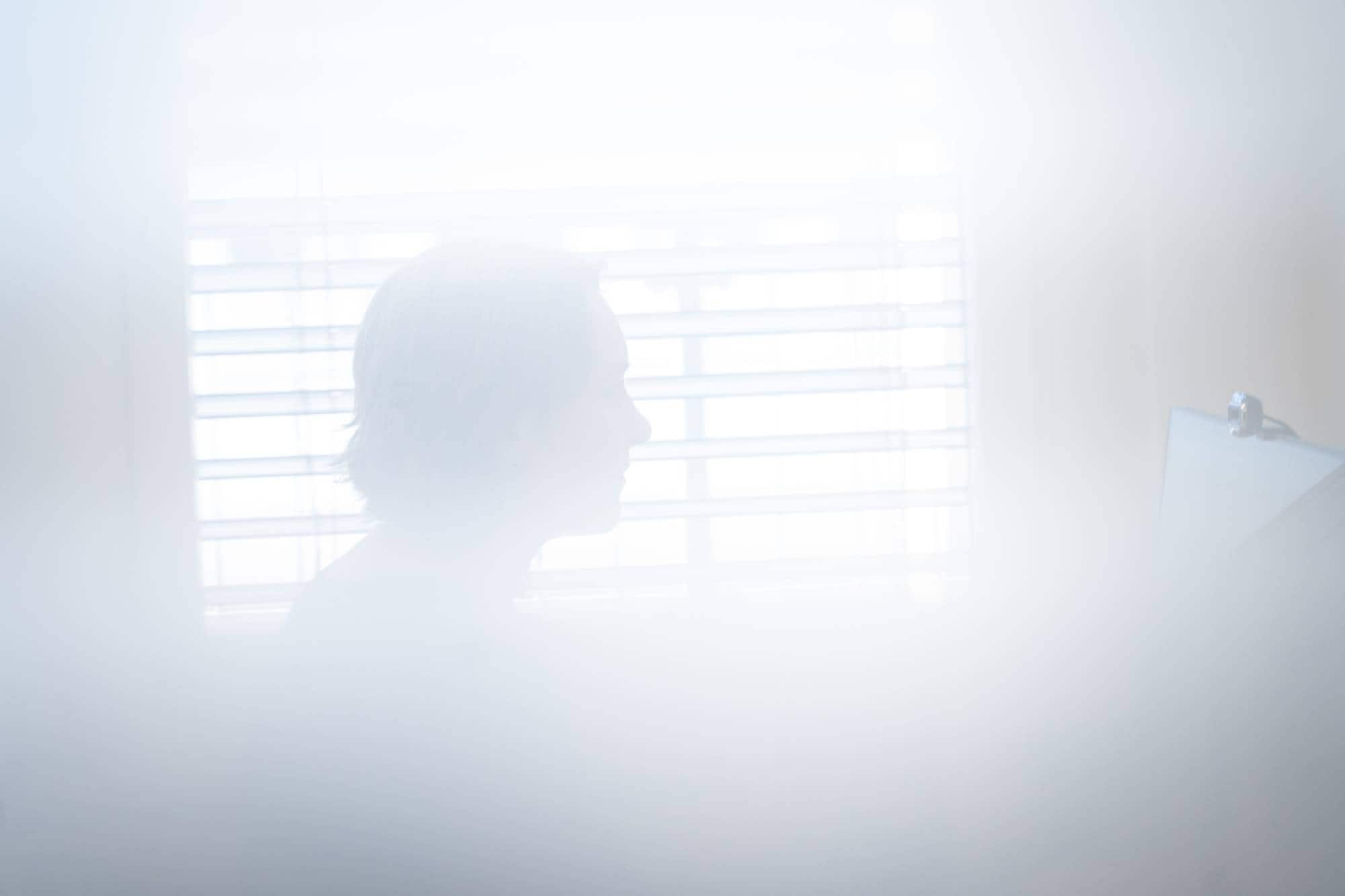 Fungerende avdelingsdirektør i Helsetilsynet om Delirium blant pasienter på sykehus. Bildet er uklart, Heidem er en vag siluett mot et vindu.