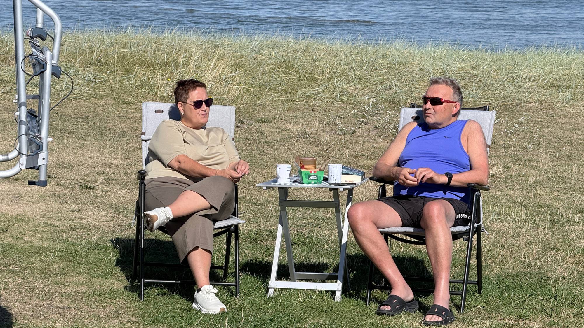 En kvinne og en mann i campingstoler utenfor campingbil. 