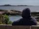Tom Nicolai Kolstad / NRK kvinne sitter på en benk med ryggen til. Hun har på svart hettegenser. Hun ser utover mot havet.