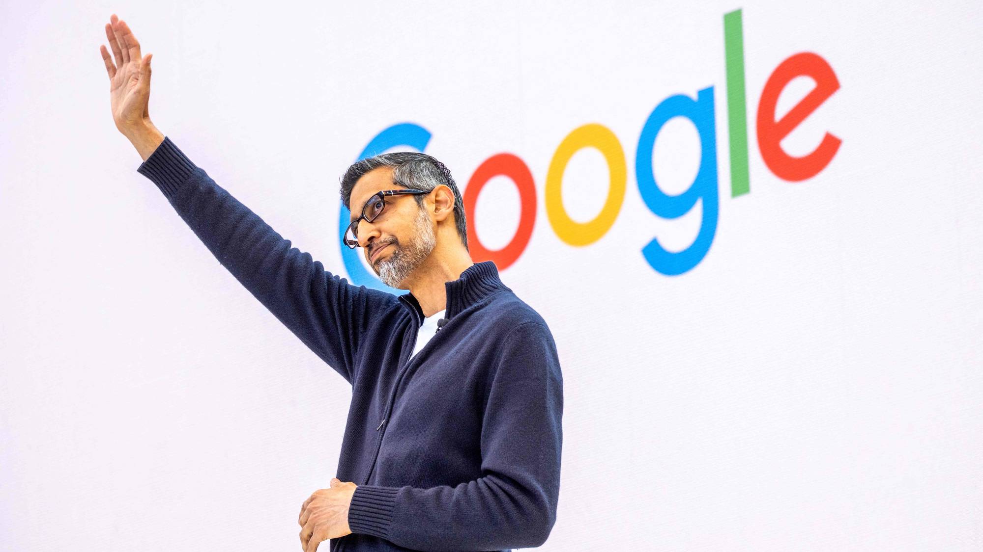 Sundar Pichai vinker foran en Google-logo. 