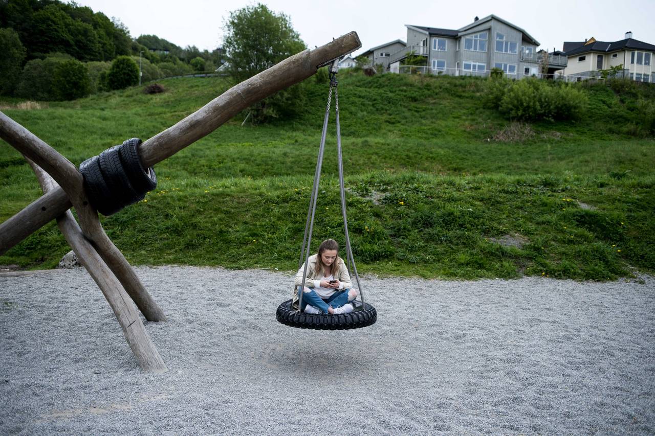 Bilde av Ingebjørg som sitter på en huske laget av et slags gummihjul. Husken er festet i et trestokk.
