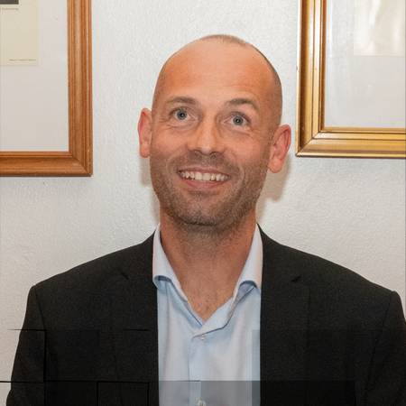 Lite bilde av en mann som smiler og ser oppover på skrå
