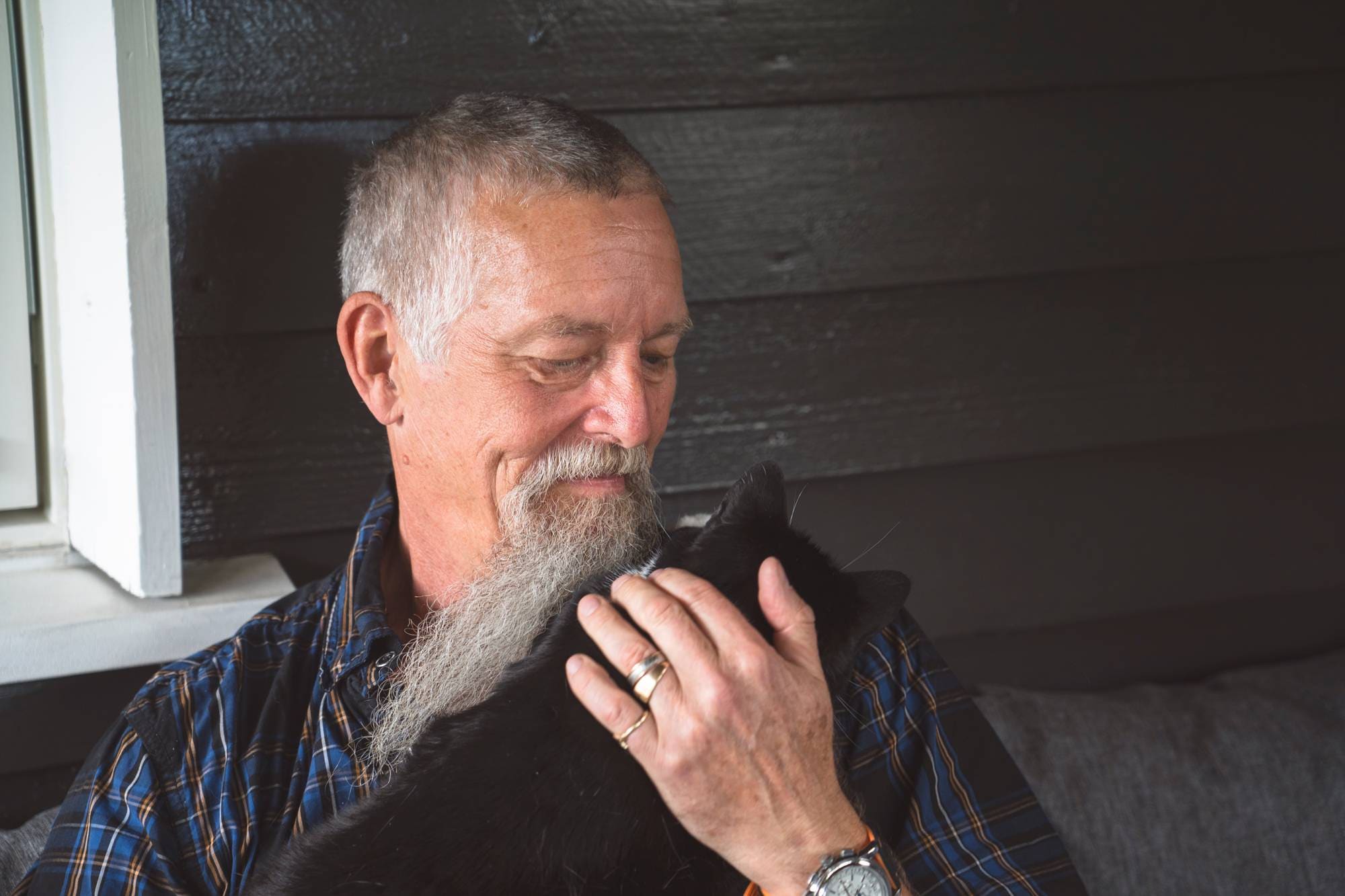 Mann med katt sitter i sofa