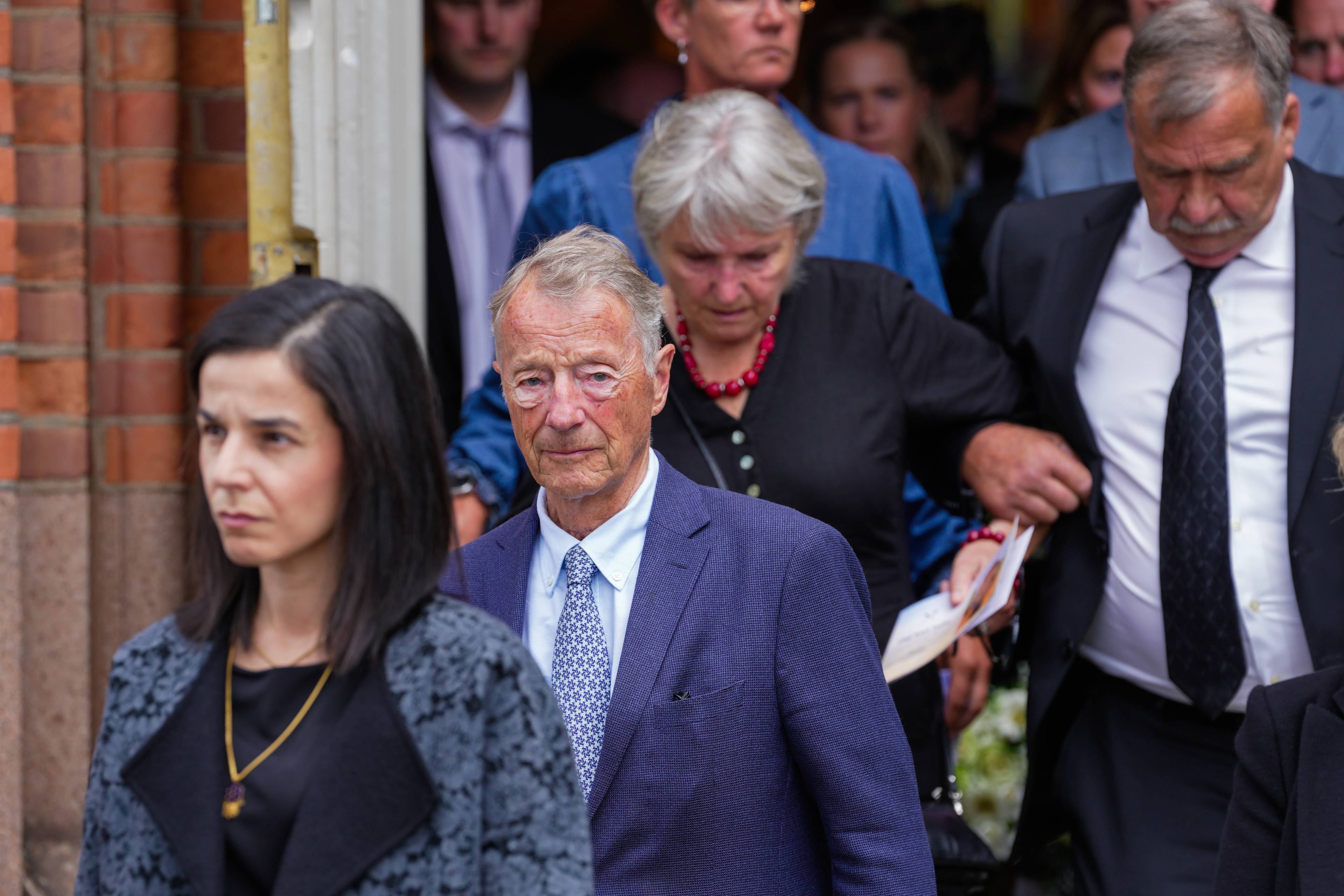 En gruppe mennesker i formelle klær går ut av en bygning.