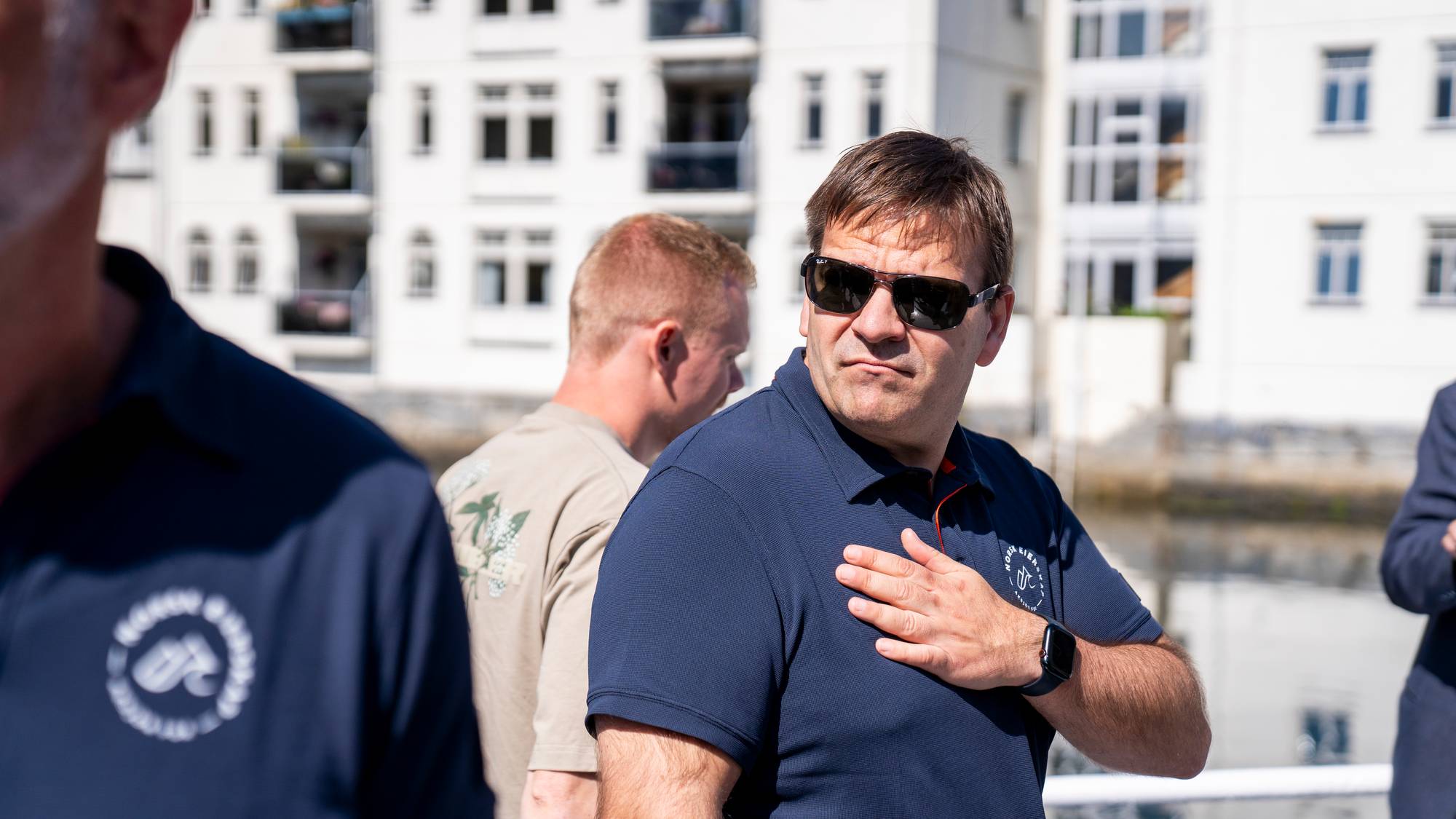 en mann med solbriller tar seg til brystet