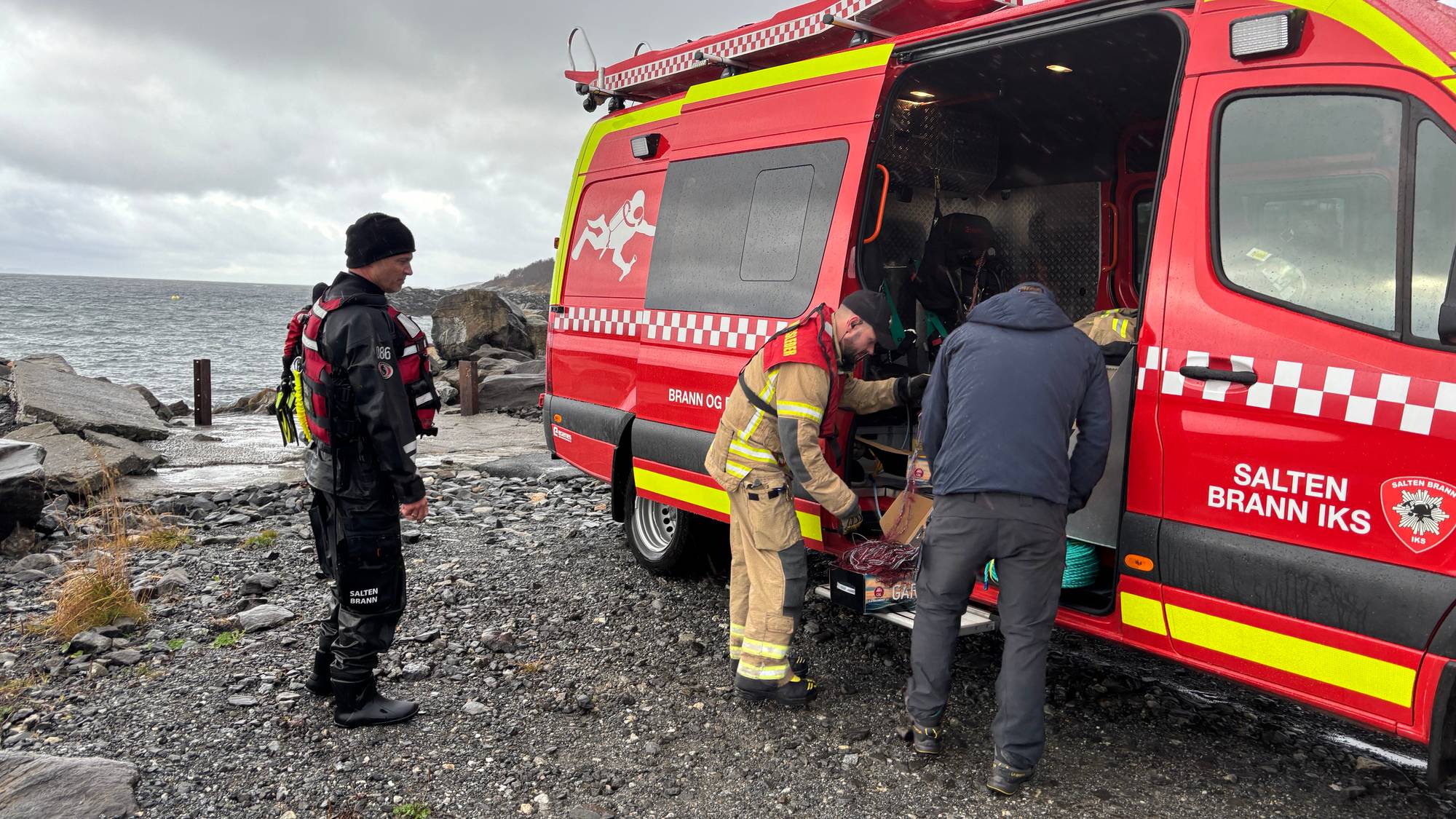 Mannskaper fra Salten brann IKS ved en rød utrykningsbil i fjæra. (Bildebeskrivelsen er laget av en KI-tjeneste)