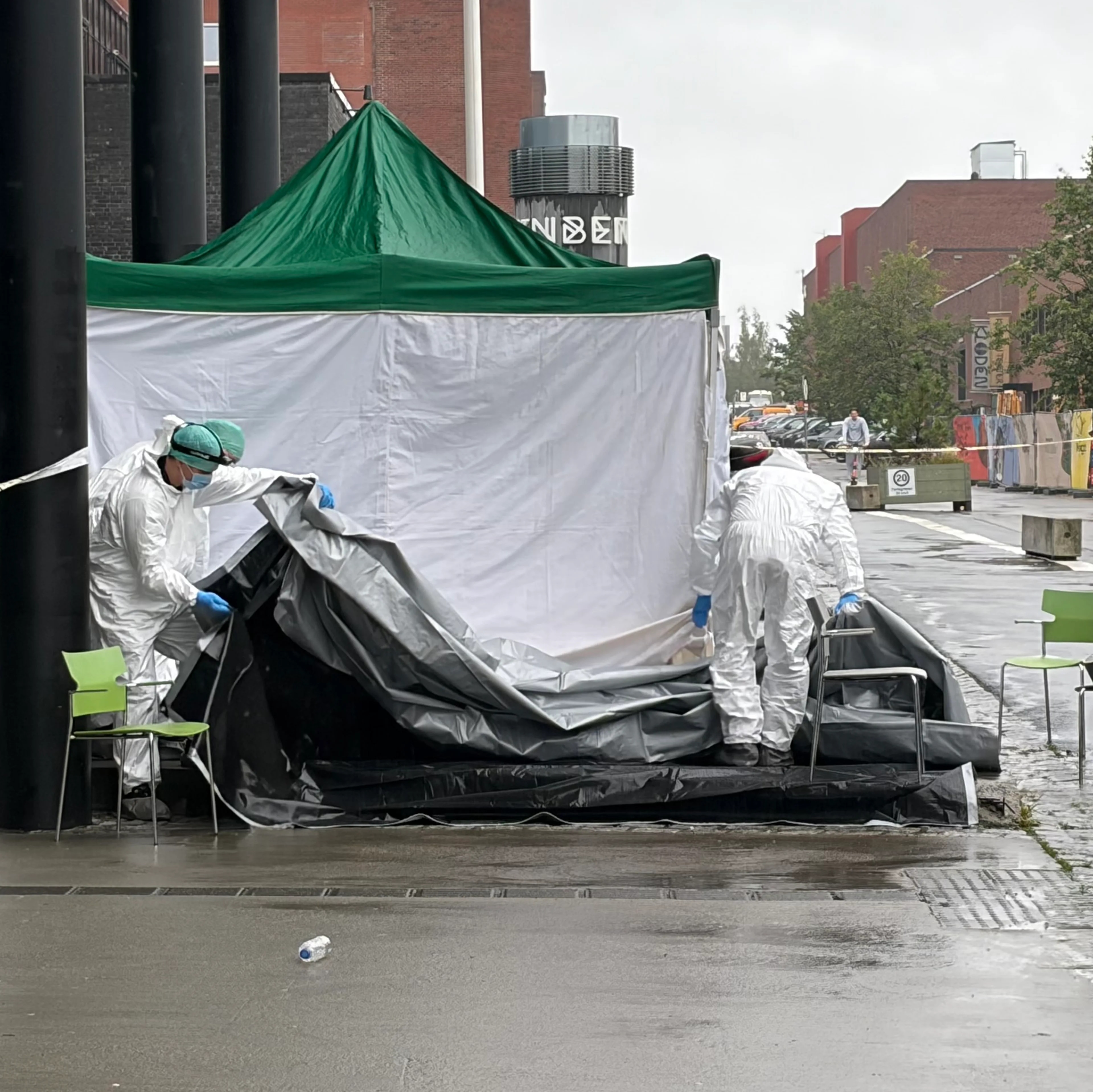 Et hvitt telt på et åsted med kjeledresskledde mennesker.