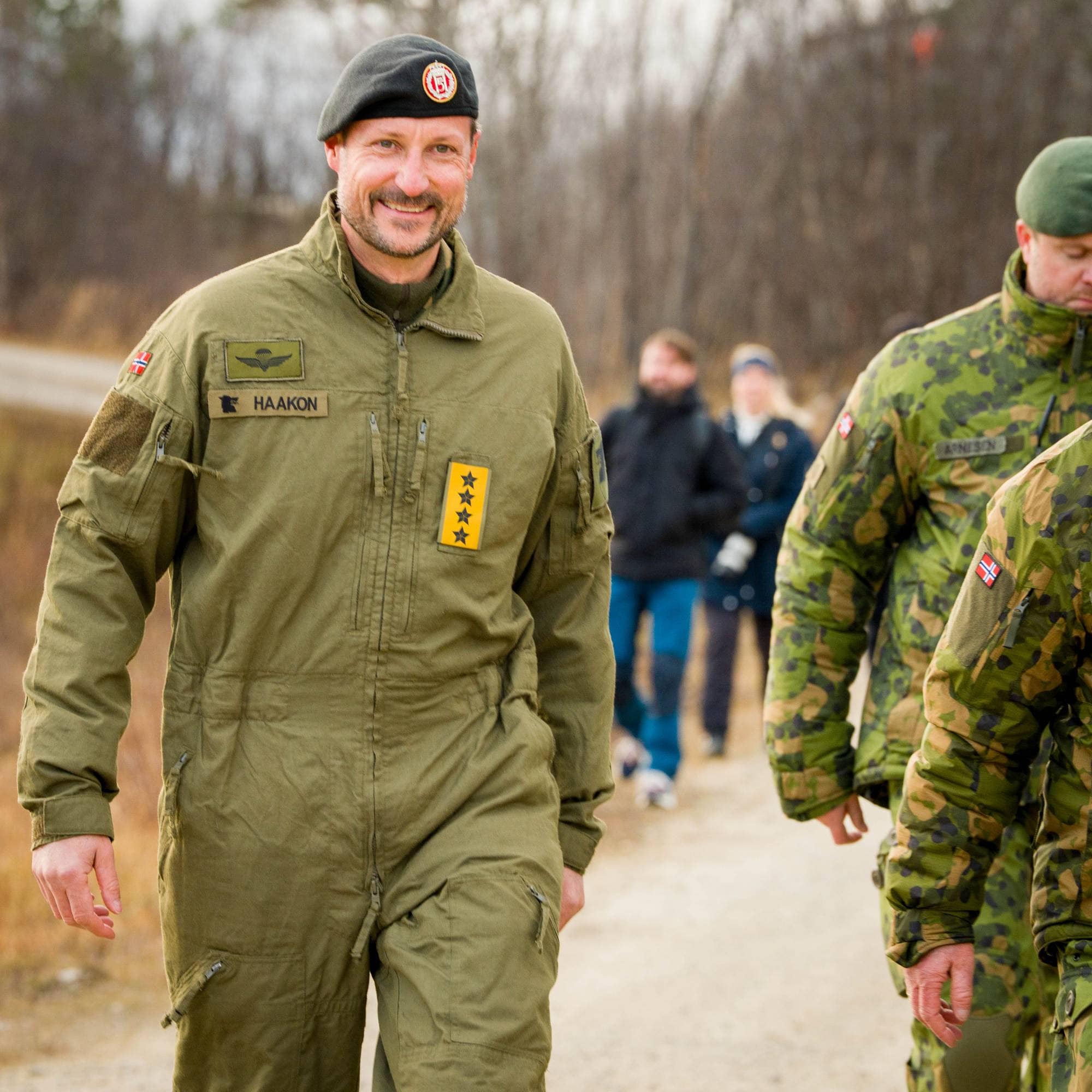 Hans majestet Kong Haakon kommer gående opp veien til skytefeltet ved Porsangmoen leir.