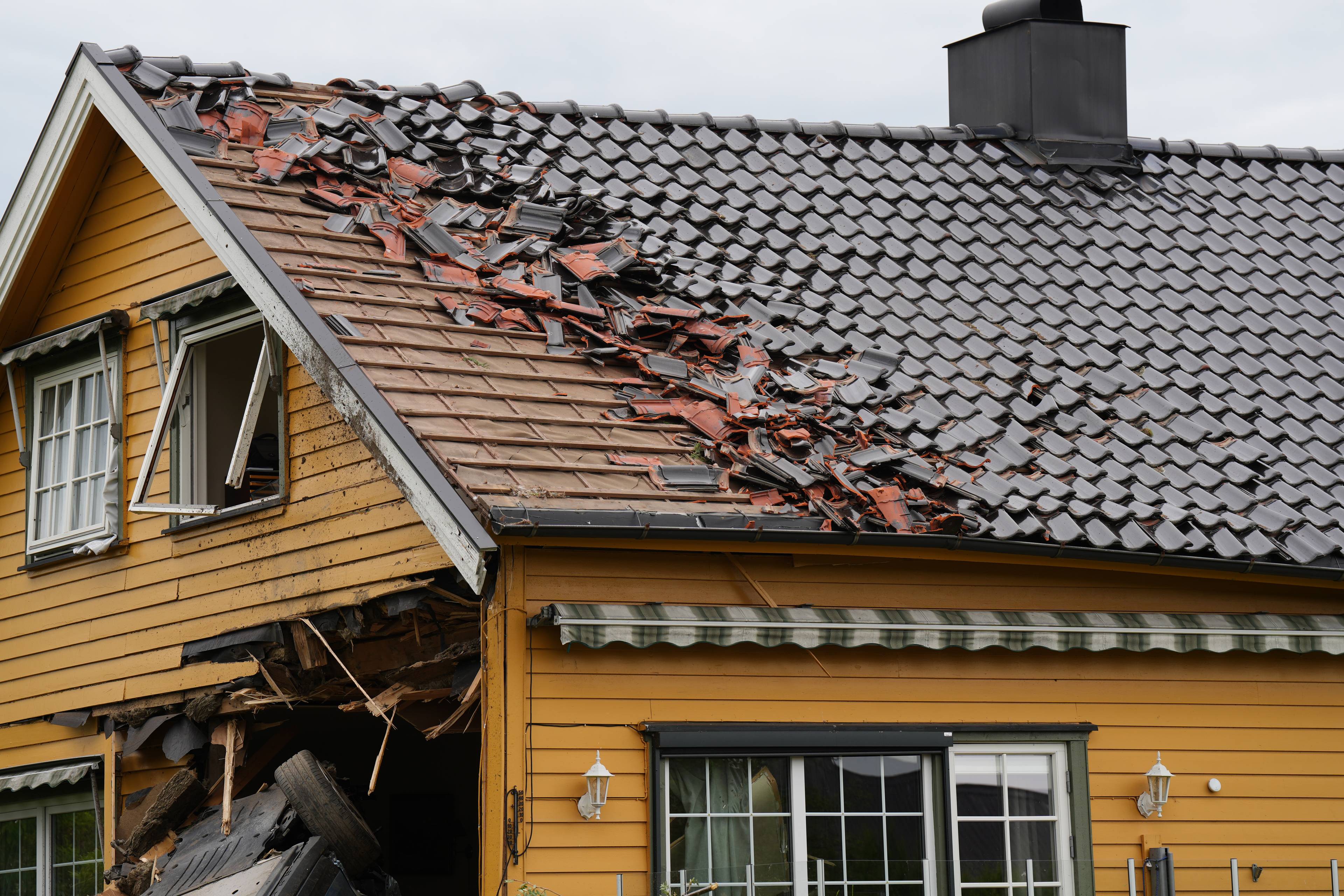 Store skader på husvegg med knuste vinduer