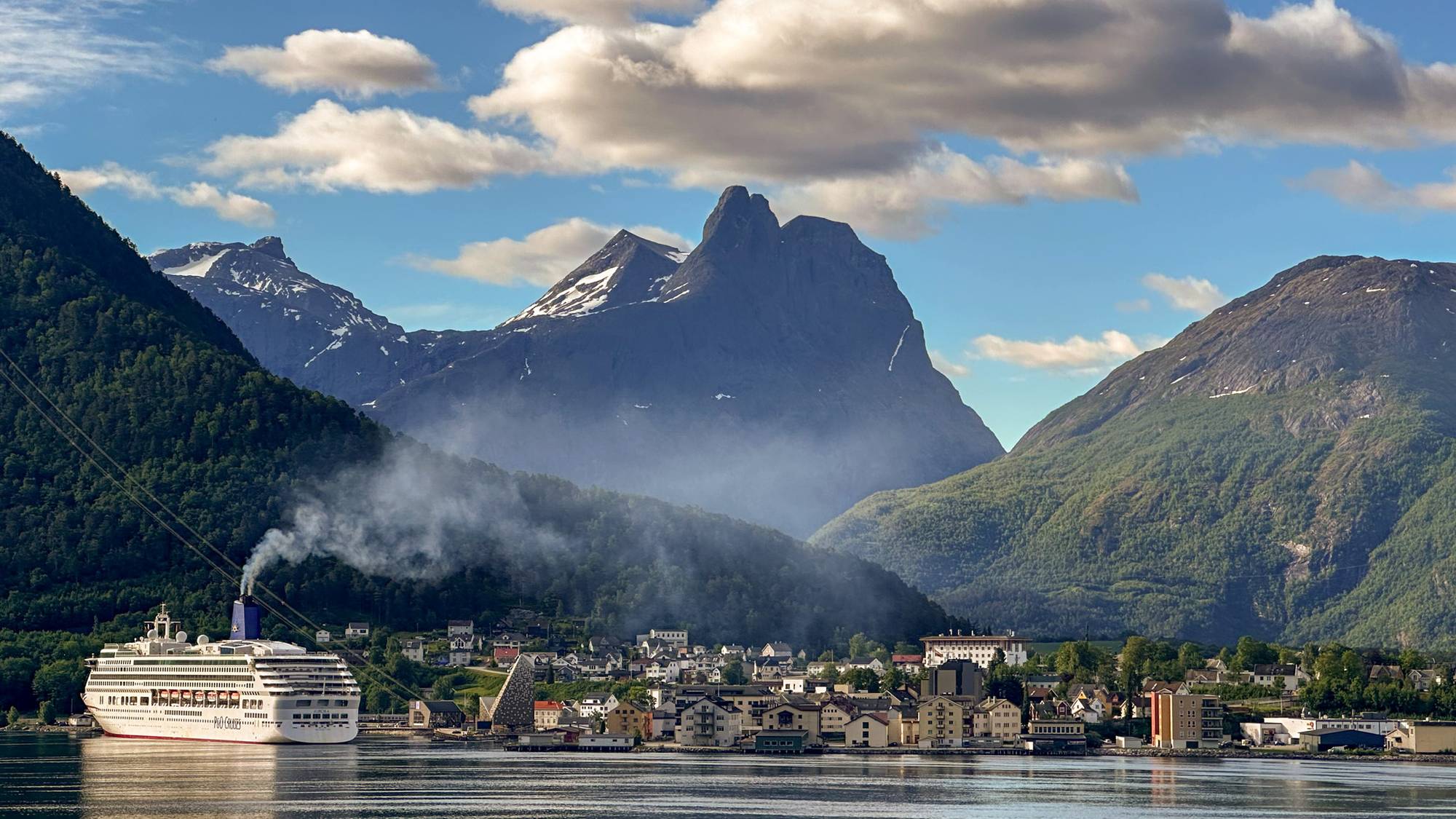 en by ved siden av en vannmasse med fjell i baksiden. 