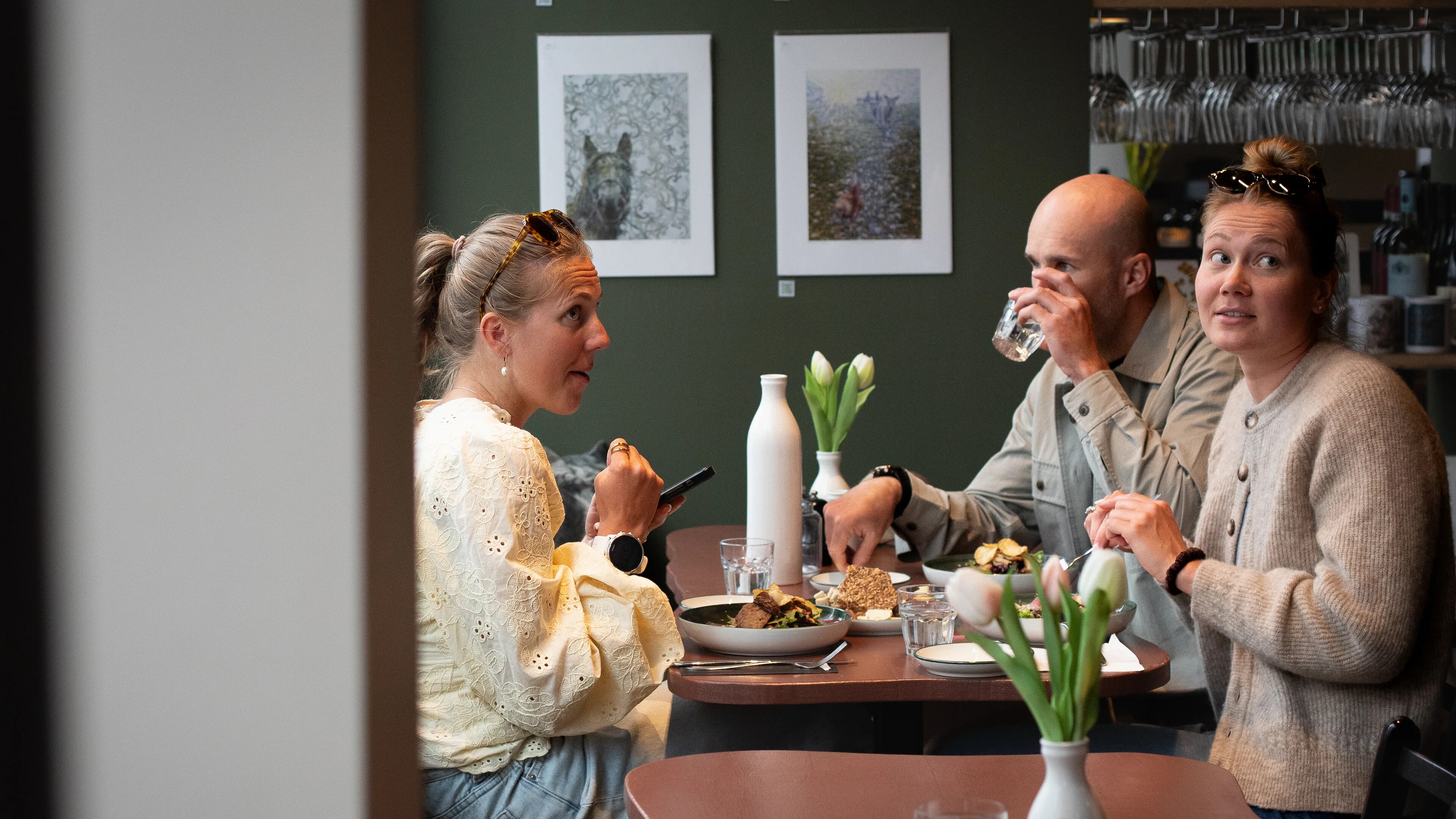 en gruppe mennesker som sitter rundt et bord med mat og spiser