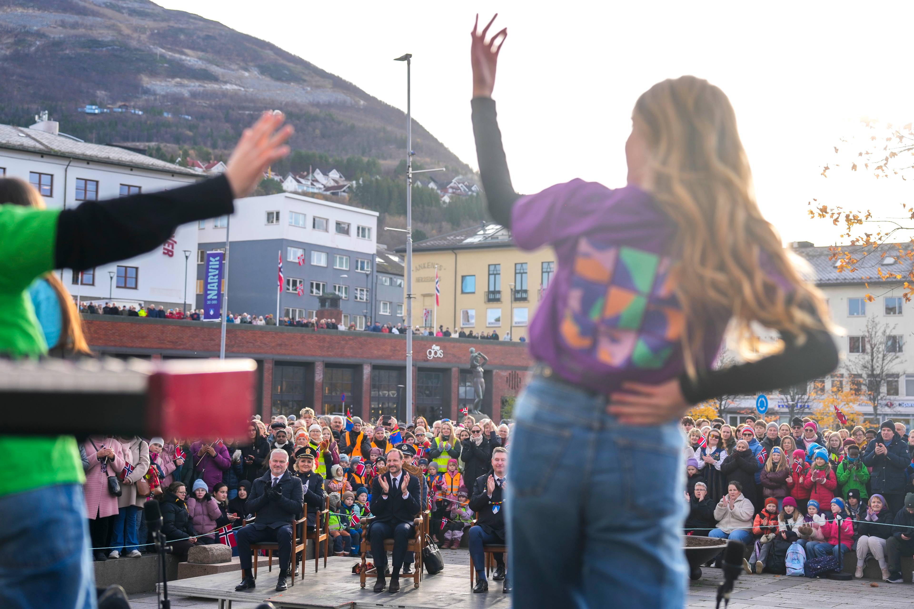 Dansere opptrer foran publikum og en sittende kronprins i Narvik. (Bildebeskrivelsen er laget av en KI-tjeneste)