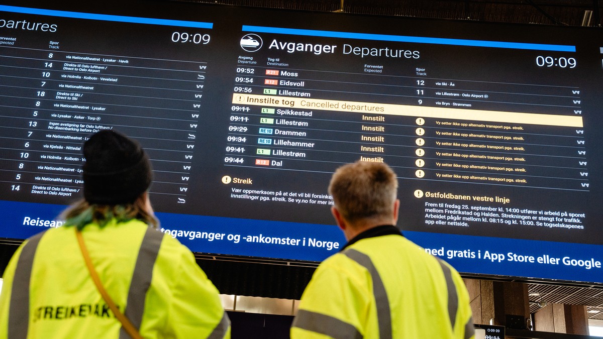 To personer i gul refleksvest ser på en digital informasjonstavle med innstilte togavganger. (Bildebeskrivelsen er laget av en KI-tjeneste) FOTO: Lars Martin Hunstad/NRK