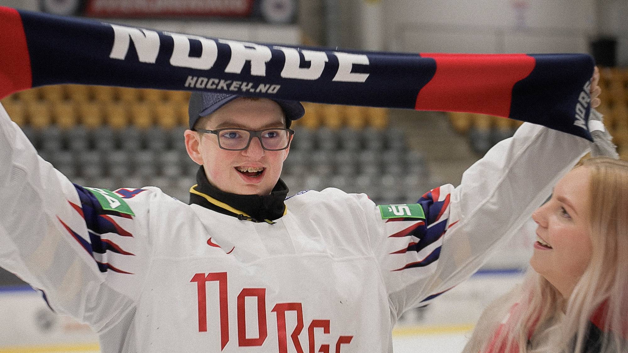 Adrian holder opp et supporterskjerf med søsteren ved sin side.