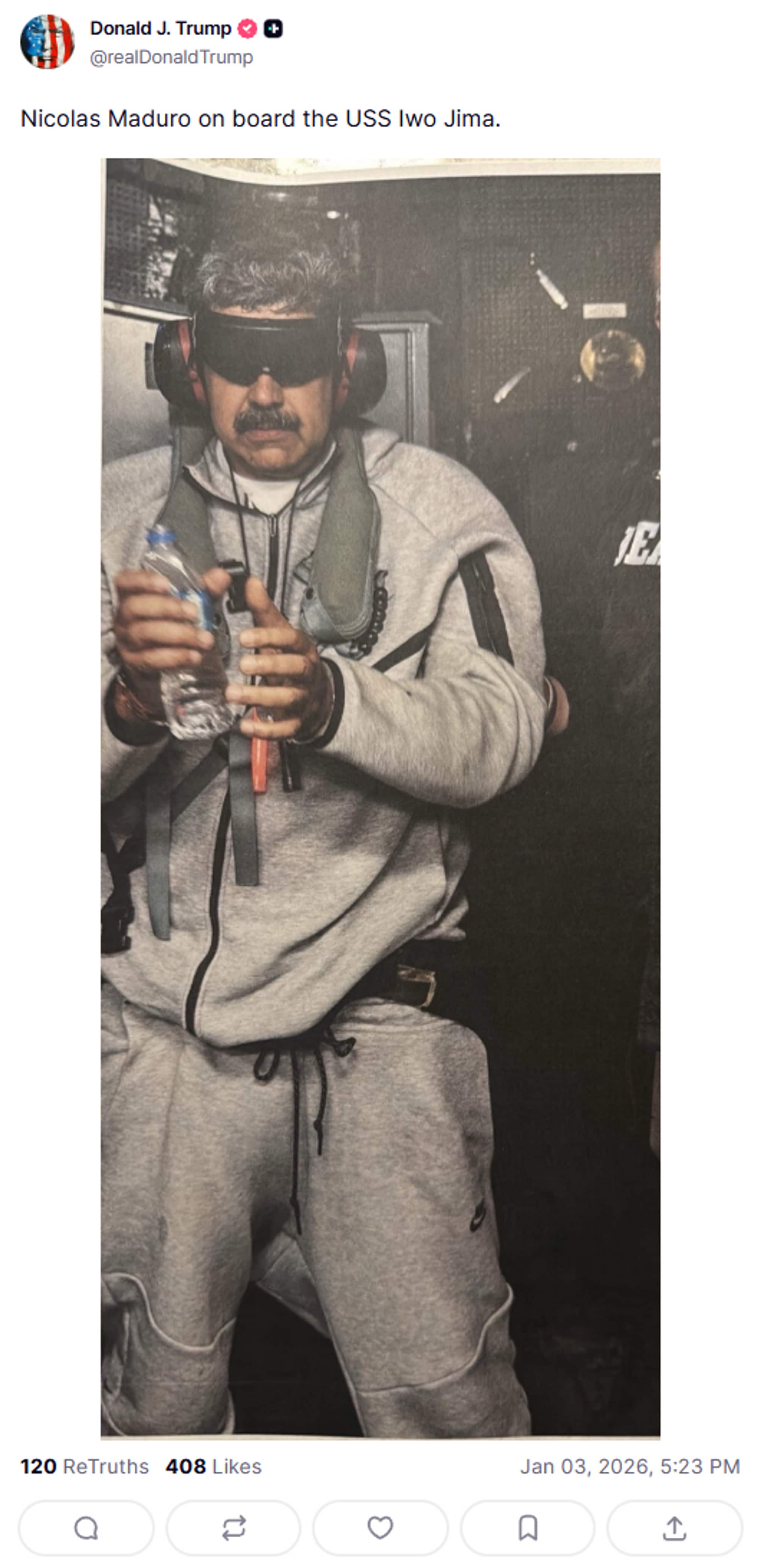 Faksimile: Donald Trump / Truth Social A person is standing on a ship with headphones and holding a bottle of water. The person is wearing gray clothing and is surrounded by dark, unidentified background elements. There is a clear focus on the individual and the action with little visual noise around. The image appears to be linked to a specific incident aboard the USS Iwo Jima.