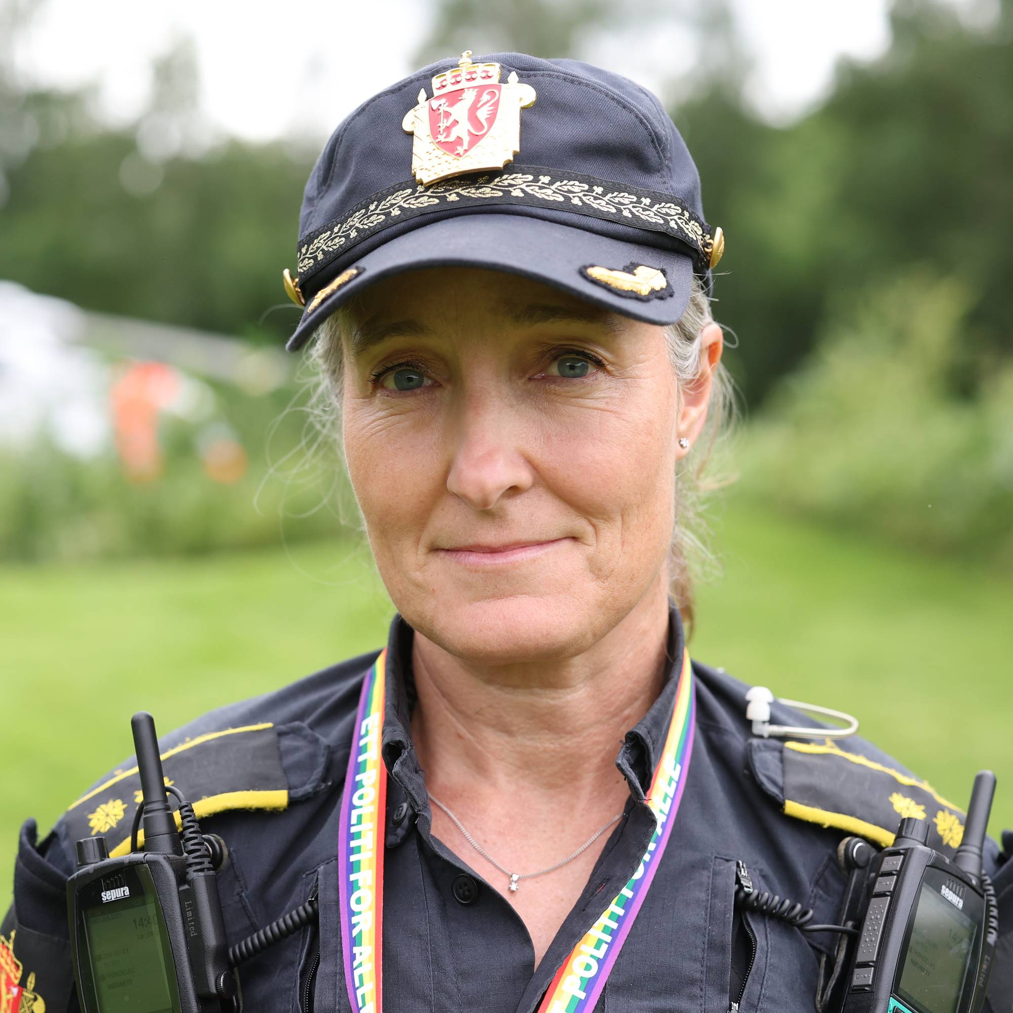 En politibetjent i uniform med et redningshelikopter i bakgrunnen. (Bildebeskrivelsen er laget av en KI-tjeneste)