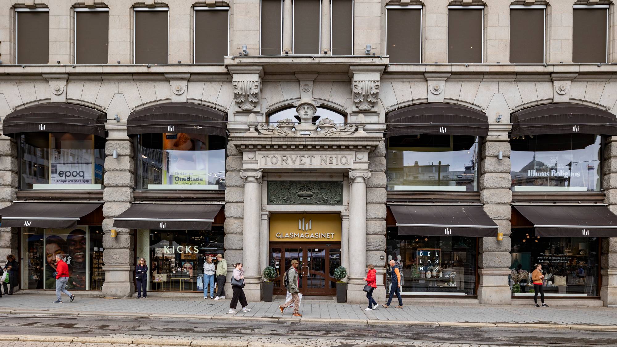 Folk går på fortauet foran inngangen til Glasmagasinet i Oslo sentrum.