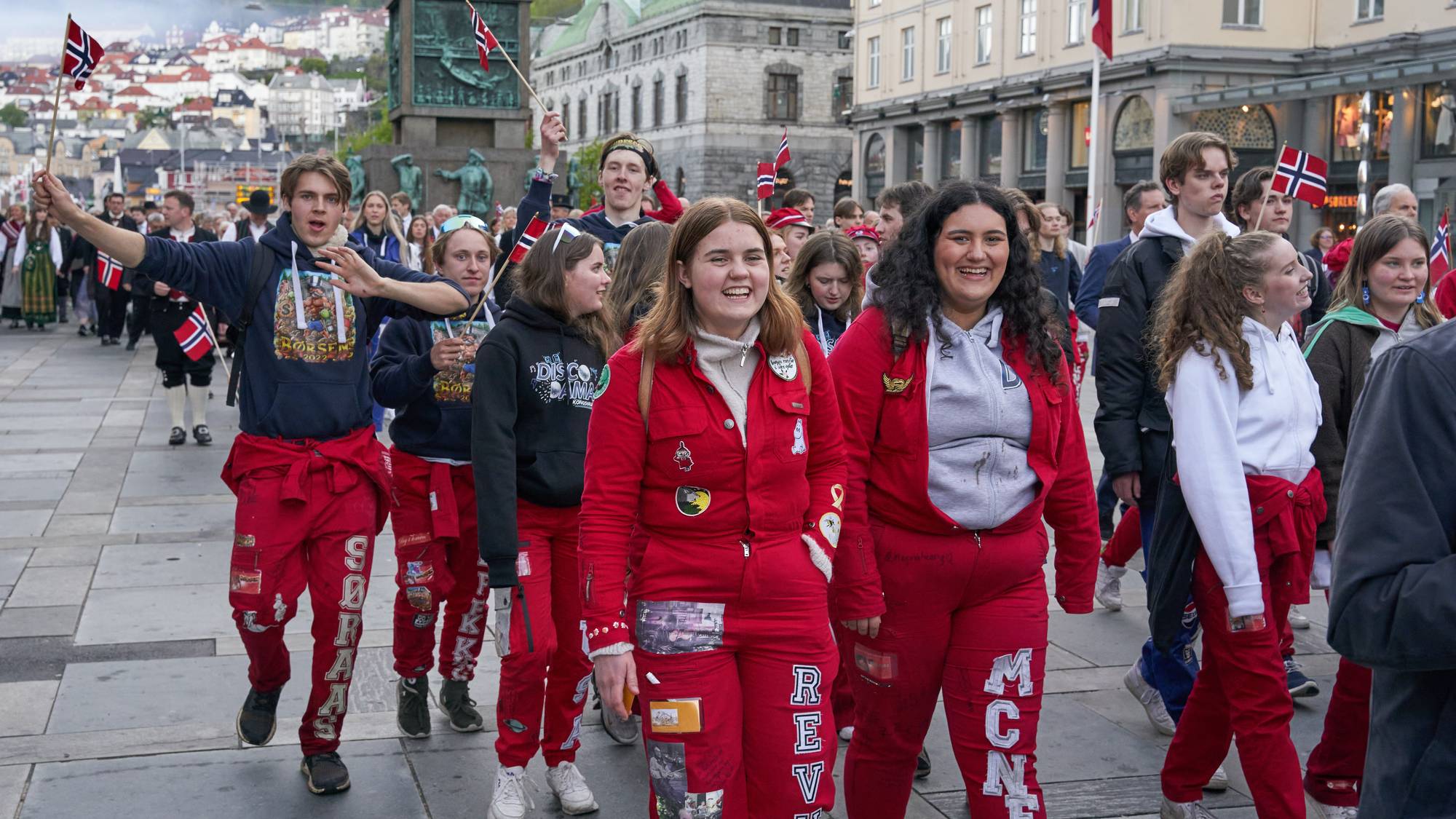 En gruppe ungdom i røde russeklær som går nedover en gate.