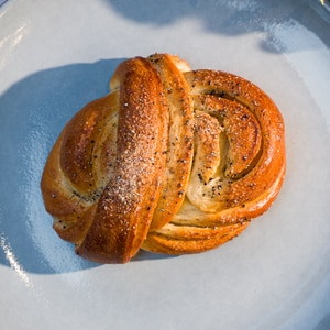 En kardemommeknute med sukker og kardemomme ligger på en blå tallerken.