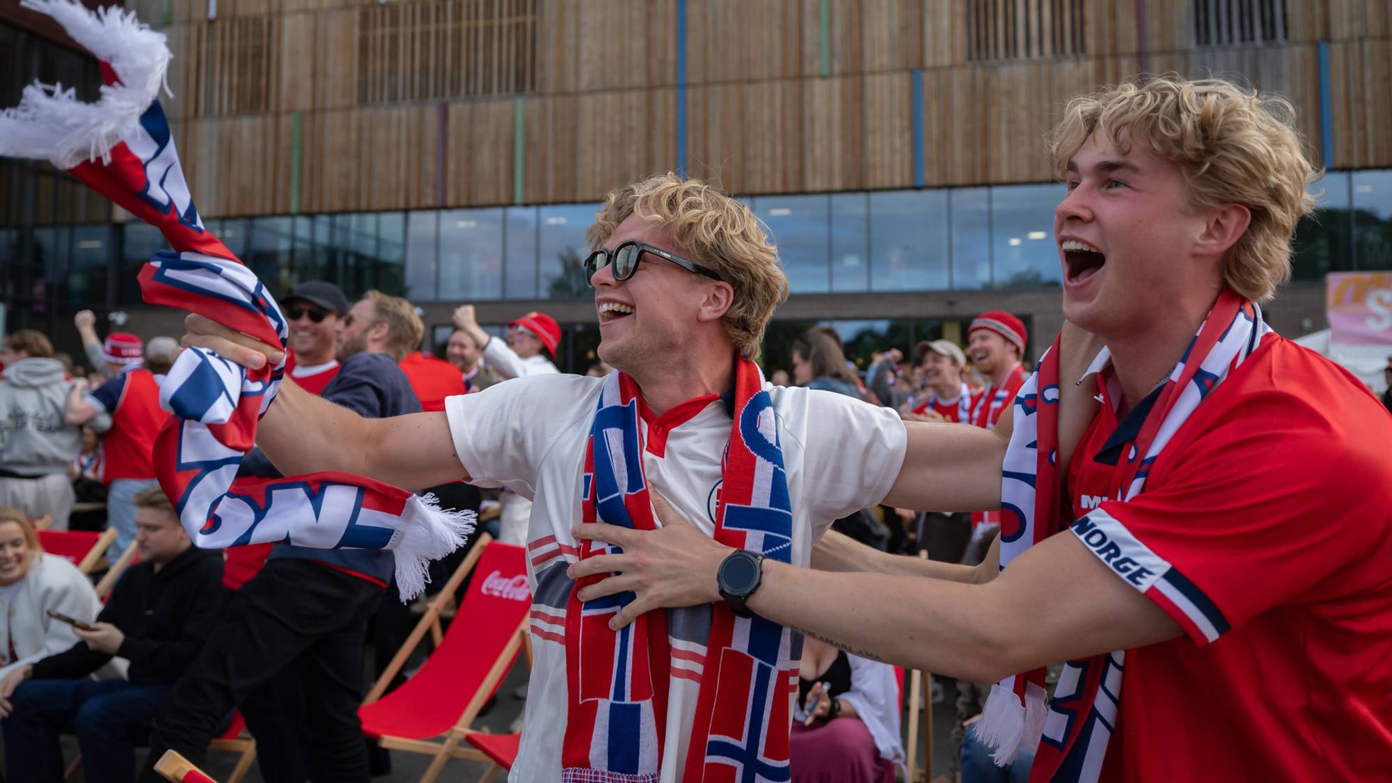 Jesper Vold og Torstein Stolp jubler vilt etter scoring i VM-kamp. De har på seg supporterutstyr og heier på Norge. Mye folk i bakgrunnen