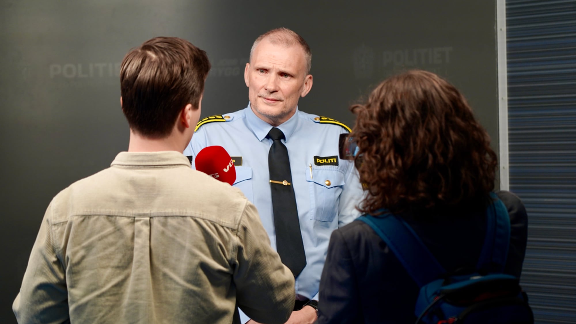En mann i politiuniform blir intervjuet
