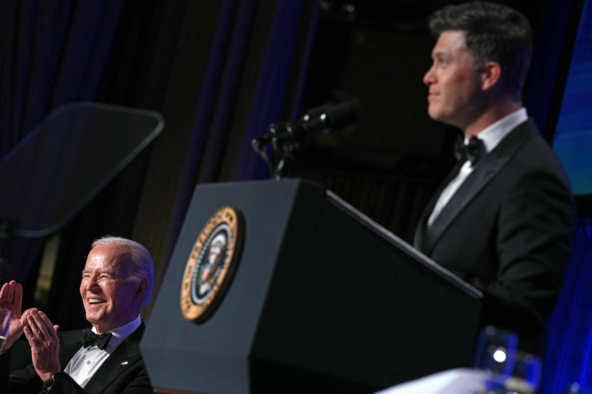 Joe Biden ler mens en person står på talerstolen.
