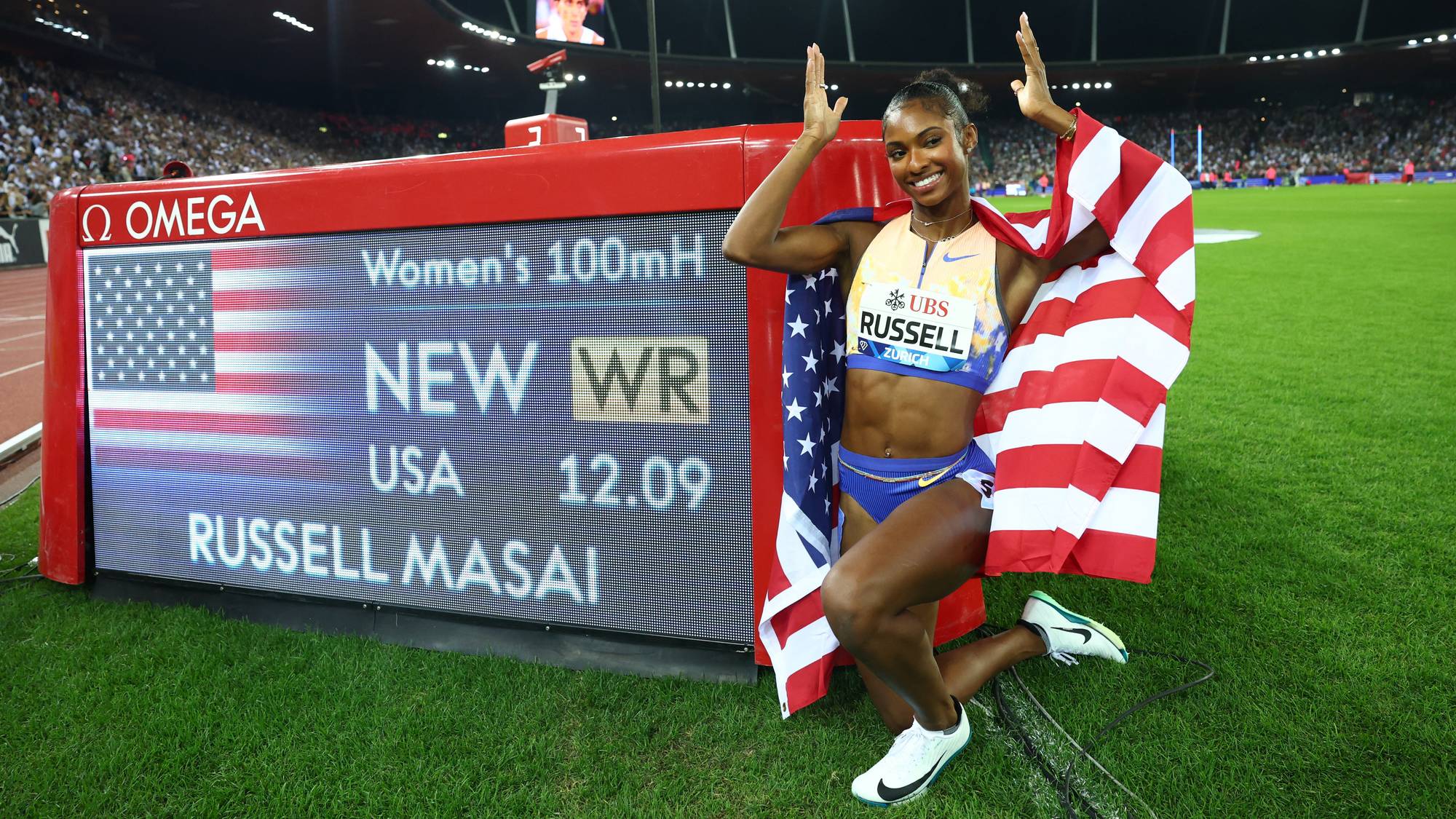 Masai Russell feirer ny verdensrekord på 100 meter hekk med et amerikansk flagg på en friidrettsbane. (Bildebeskrivelsen er laget av en KI-tjeneste)