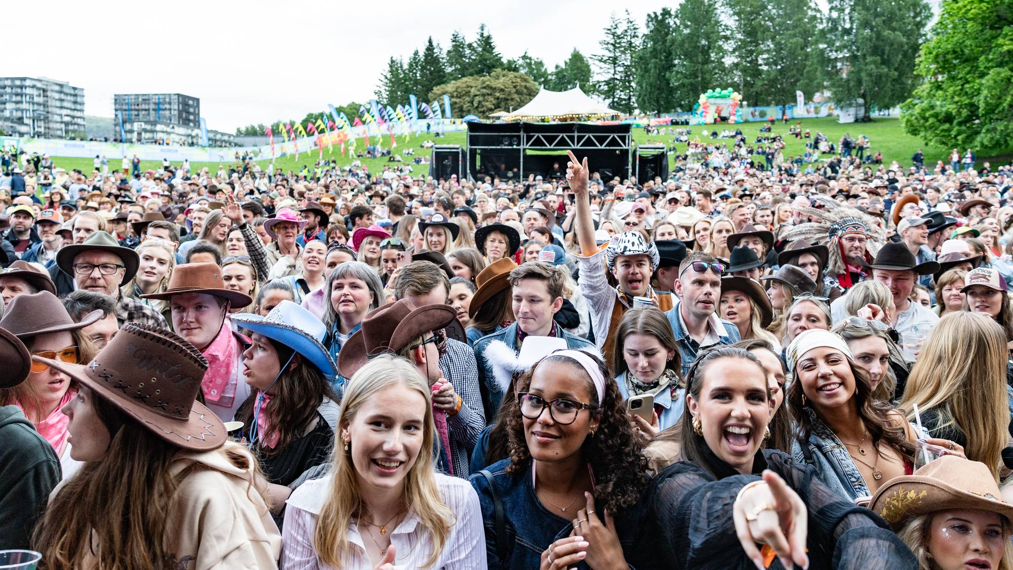 Publikum på en utendørsfestival. Mange har på seg cowboyhatter. En scene med lys og lydutstyr er synlig i bakgrunnen. (Bildebeskrivelsen er laget av en KI-tjeneste)