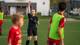 Foto: Fredrik Pedersen / NRK Mia Lahus Kise dømmer en fotballkamp. Hun er kledd i svart og rekker den ene hånden opp i været. Spillerne følger med på hennes beskjed.