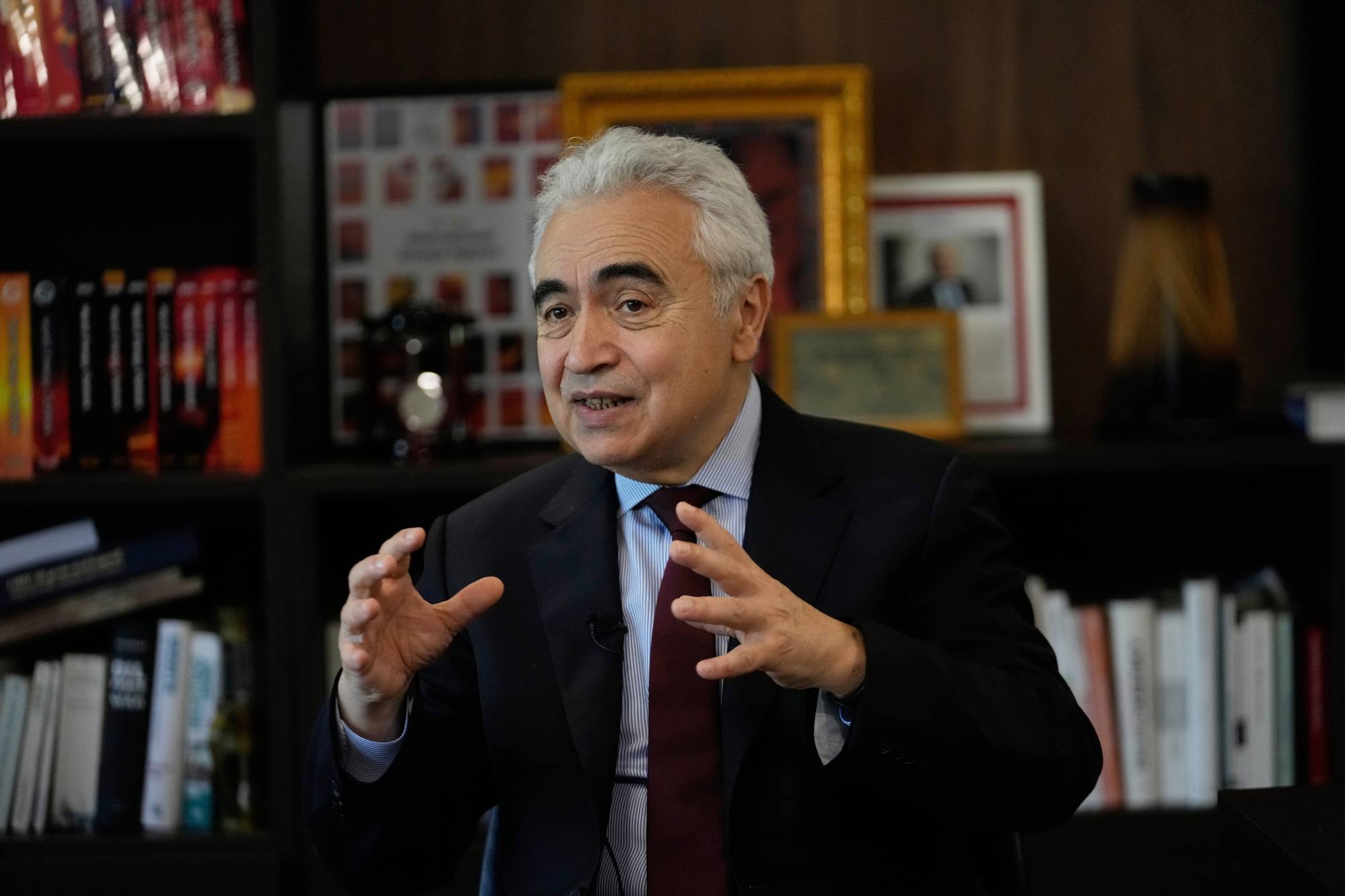 Fatih Birol sitter foran en bokhylle og gestikulerer mens han snakker. (Bildebeskrivelsen er laget av en KI-tjeneste)