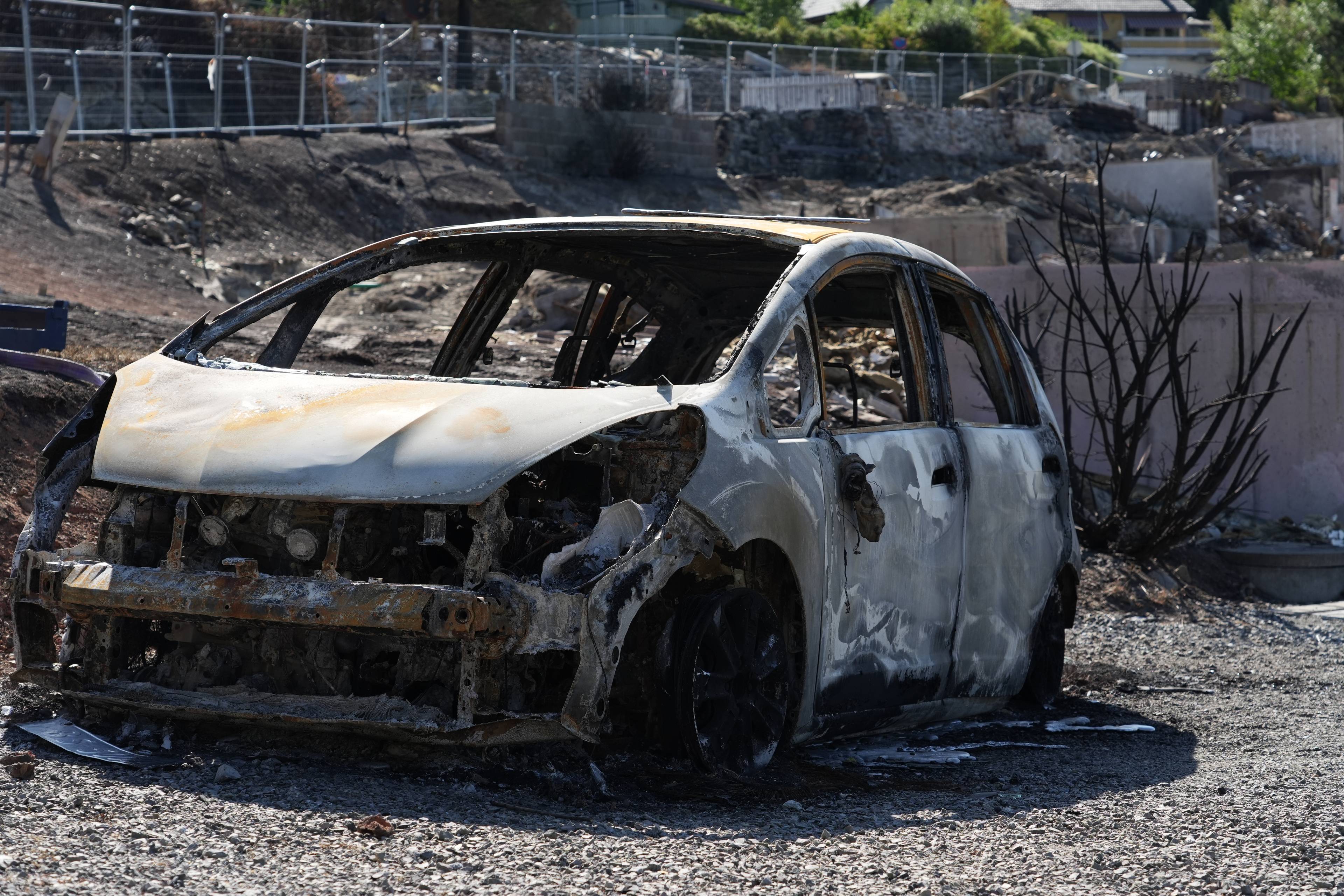 Utbrent bilvrak står igjen i et område preget av brannskader. (Bildebeskrivelsen er laget av en KI-tjeneste)