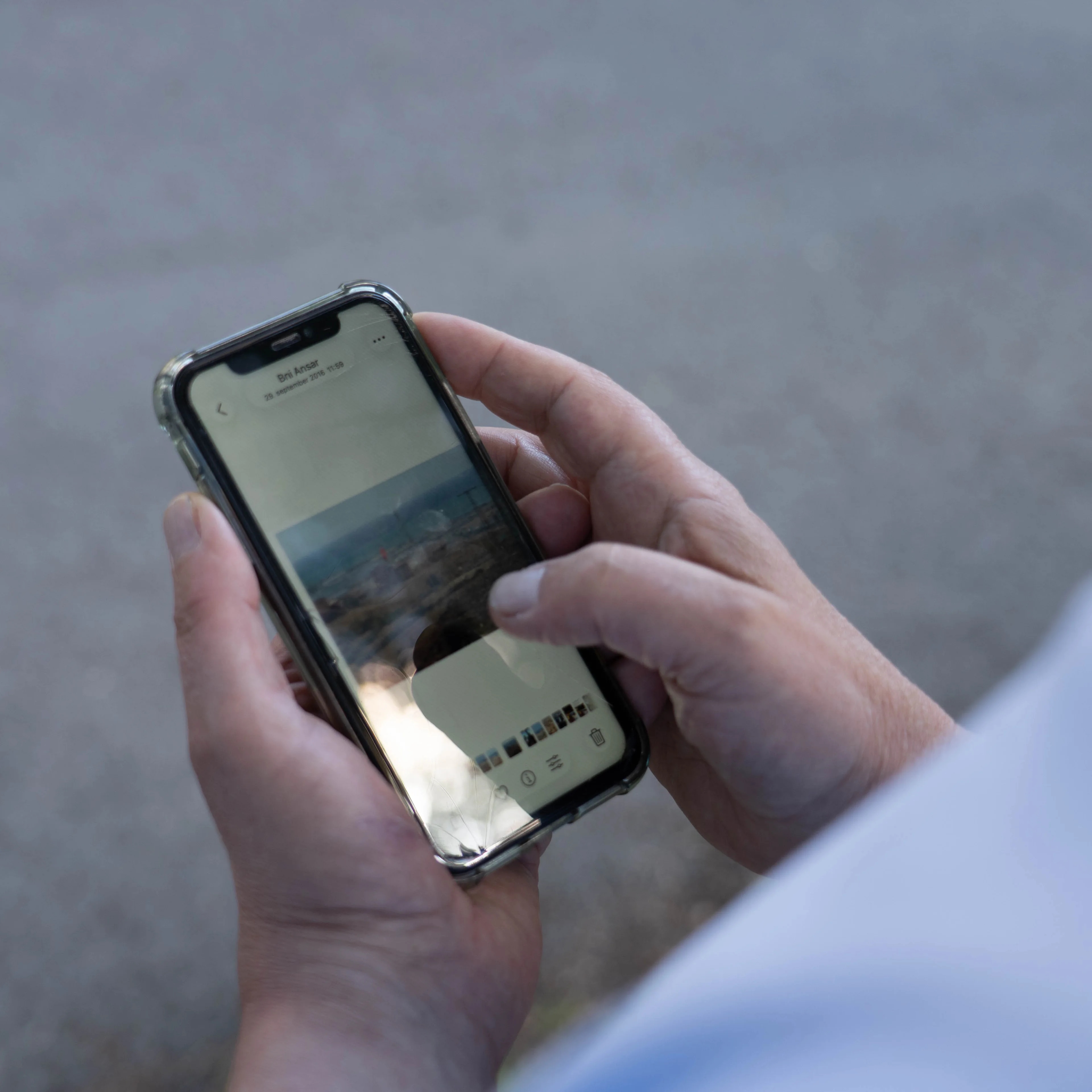En person holder en smarttelefon og blar gjennom bilder i et fotogalleri. (Bildebeskrivelsen er laget av en KI-tjeneste)