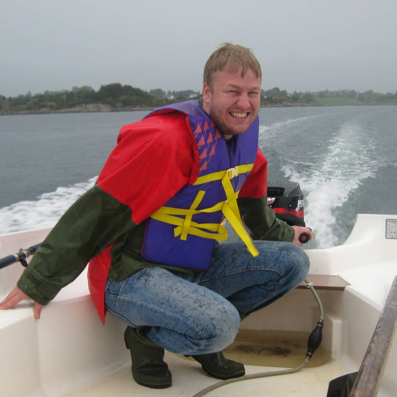 Ole Johnny Broholt Bakke sitter i en båt med flytevest og smiler til kamera