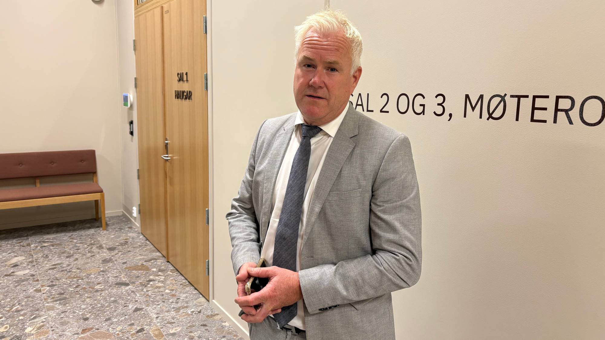 En mann i dress står innendørs.