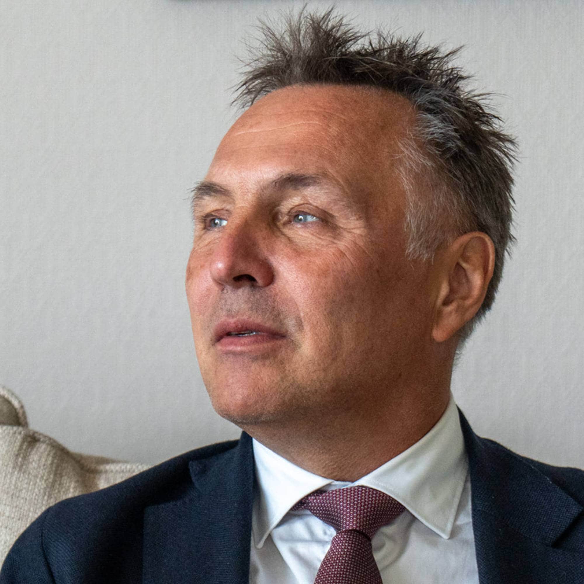 Tore O. Sandvik i dress sittende på en sofa