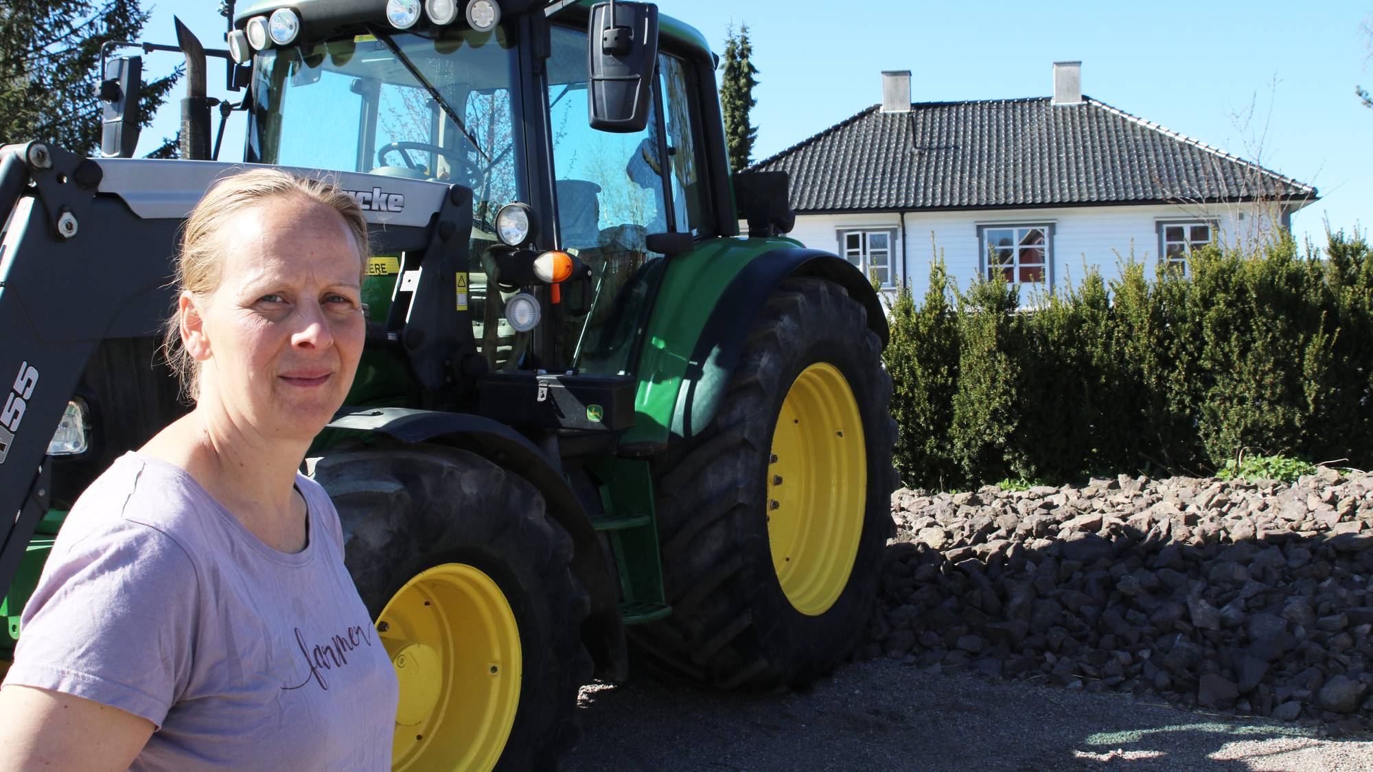 Kvinne står foran en grønn traktor
