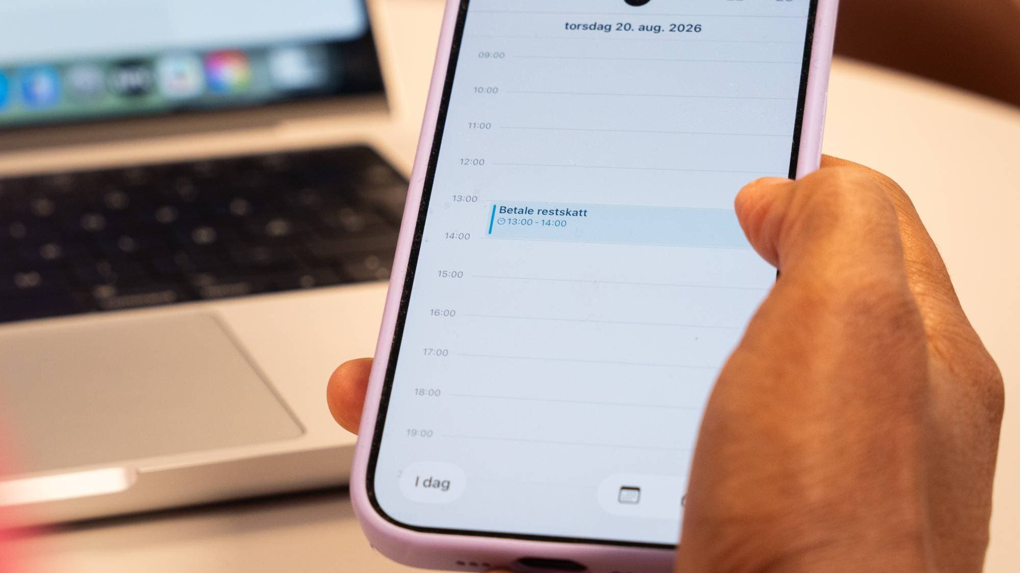 En person som holder en telefon med kalenderen oppe.