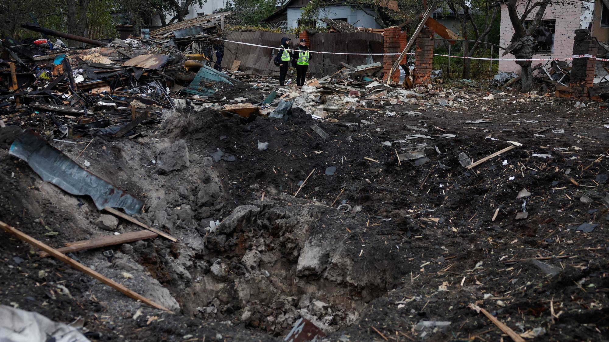 Police officers look at a crater that appeared in a residential area after overnight Russian missile strikes, amid Russia's attack on Ukraine, in Kyiv, Ukraine October 22, 2026. REUTERS/Valentyn Ogirenko REFILE - FIXING TYPO IN "CRATER".
