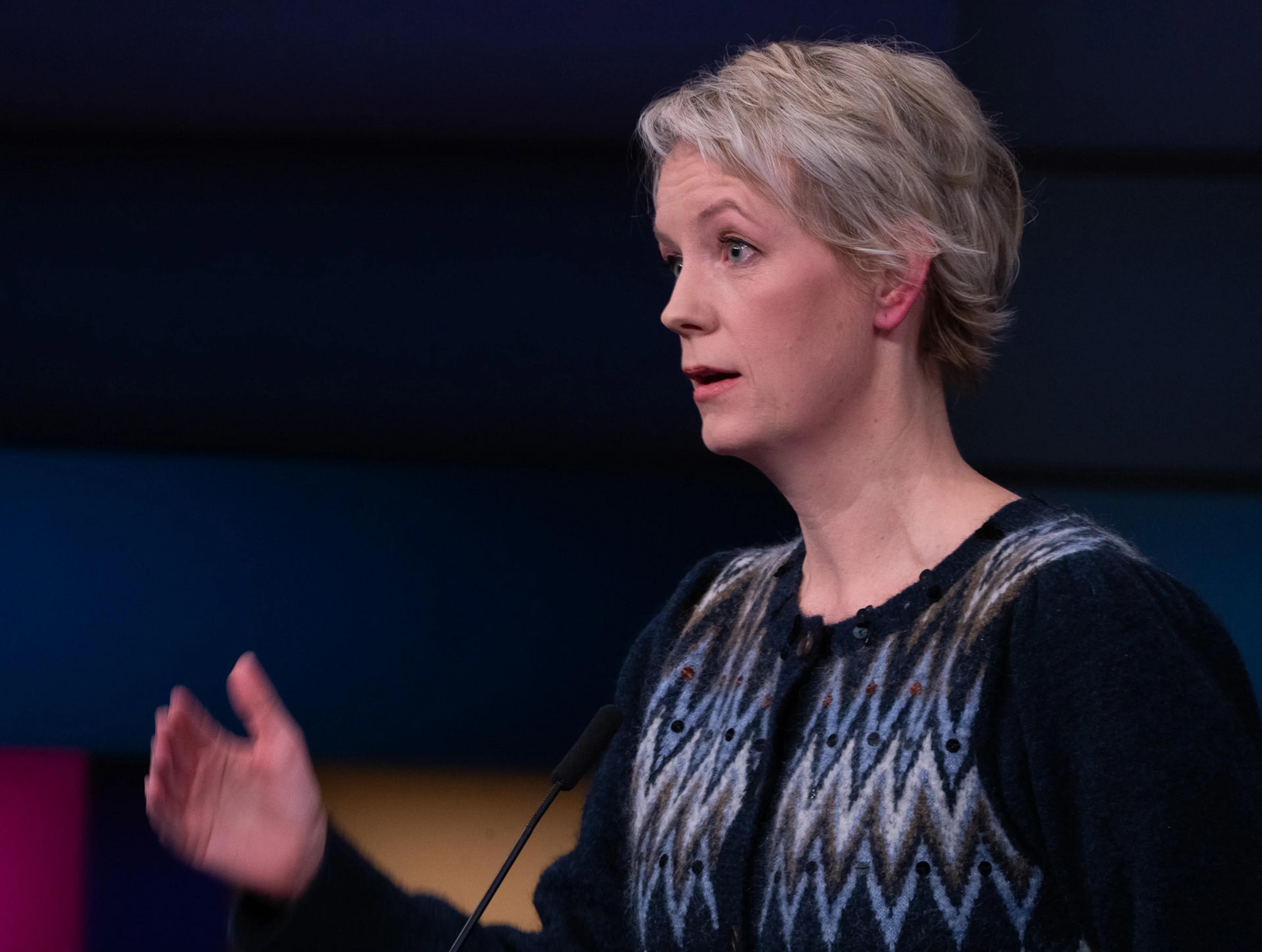 Ingrid Fiskaa (SV) i profil fra Debatten på NRK. Hun ser alvorlig ut, har på seg strikket cardigan som er svart og blåmønstret. Hun har kortklipt blondt hår.