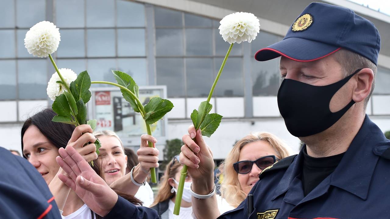 Hviterussiske demonstranter vifter med blomstene foran politiet, som ber dem fjerne seg i Minsk, Hviterussland.
